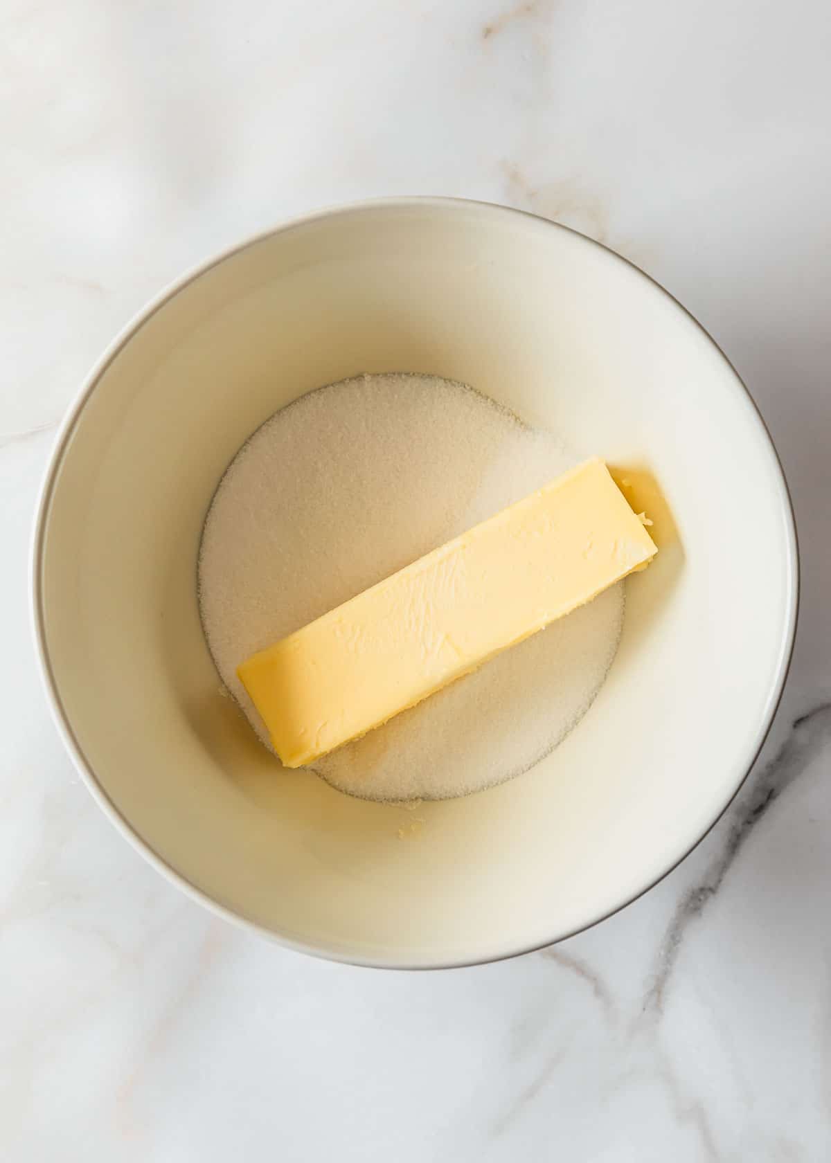 A white bowl of sugar and butter on a white counter.