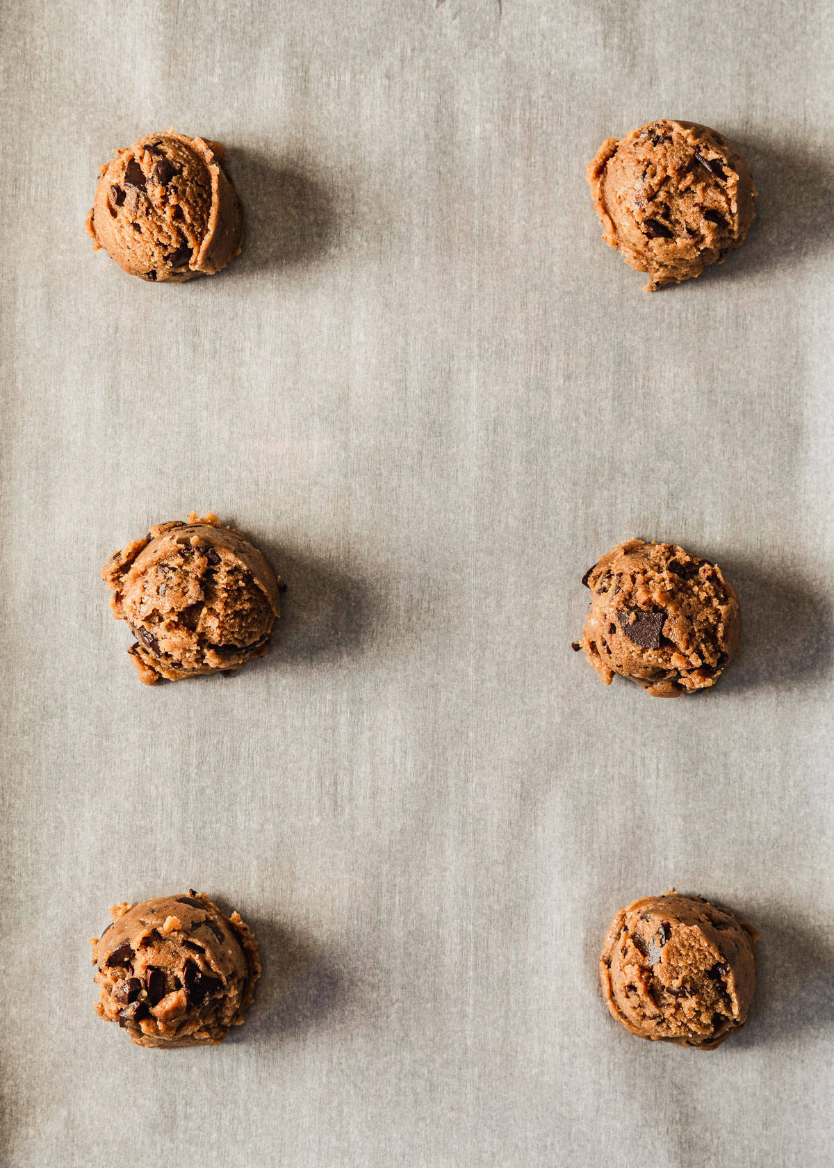 Raw small batch chocolate chip cookies on parchment paper.