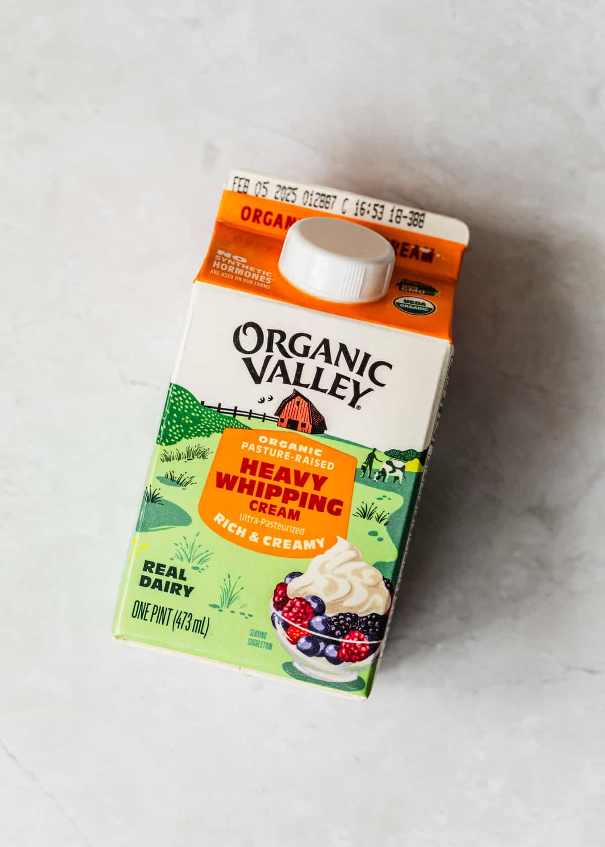 A pint of heavy whipping cream on a white counter.