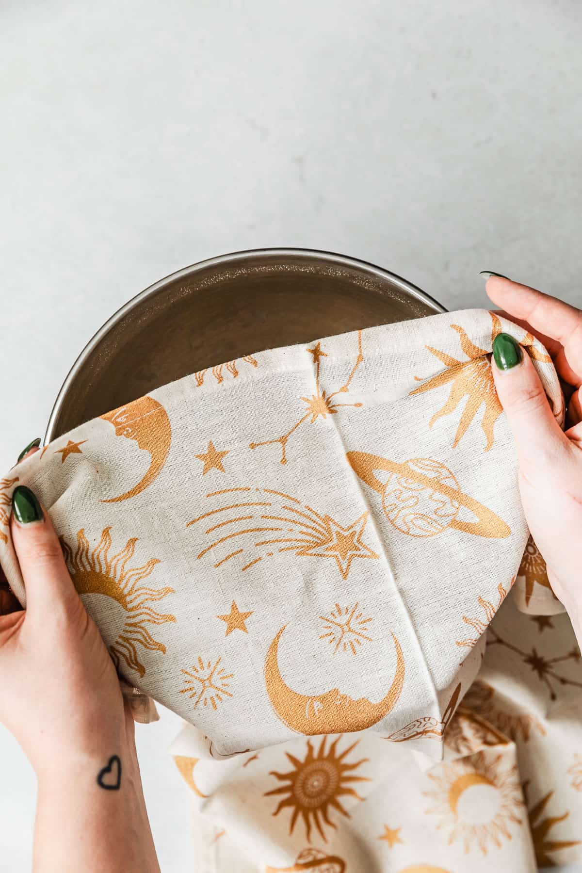 Hands covering a silver bowl with a linen.