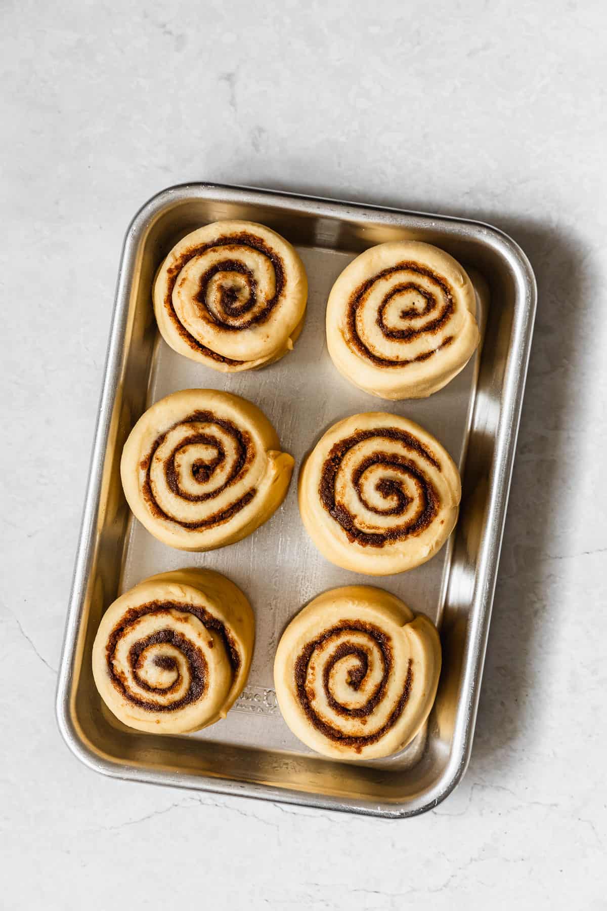 A pan of raw small batch cinnamon rolls on a white counter.