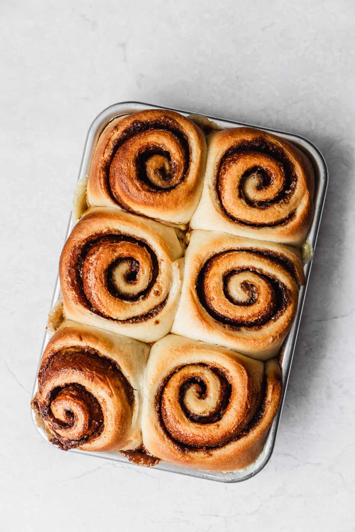 A pan of baked small batch cinnamon rolls on a marble counter.