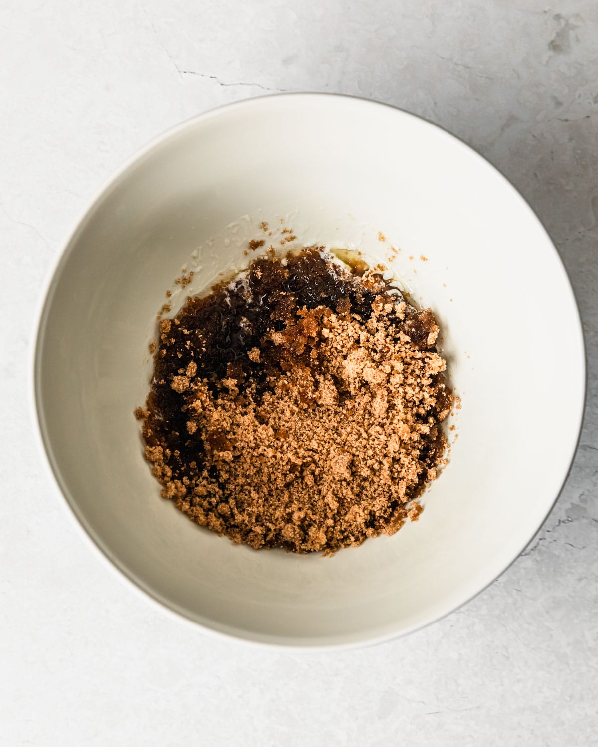 A white bowl of melted butter and brown sugar on a grey counter.