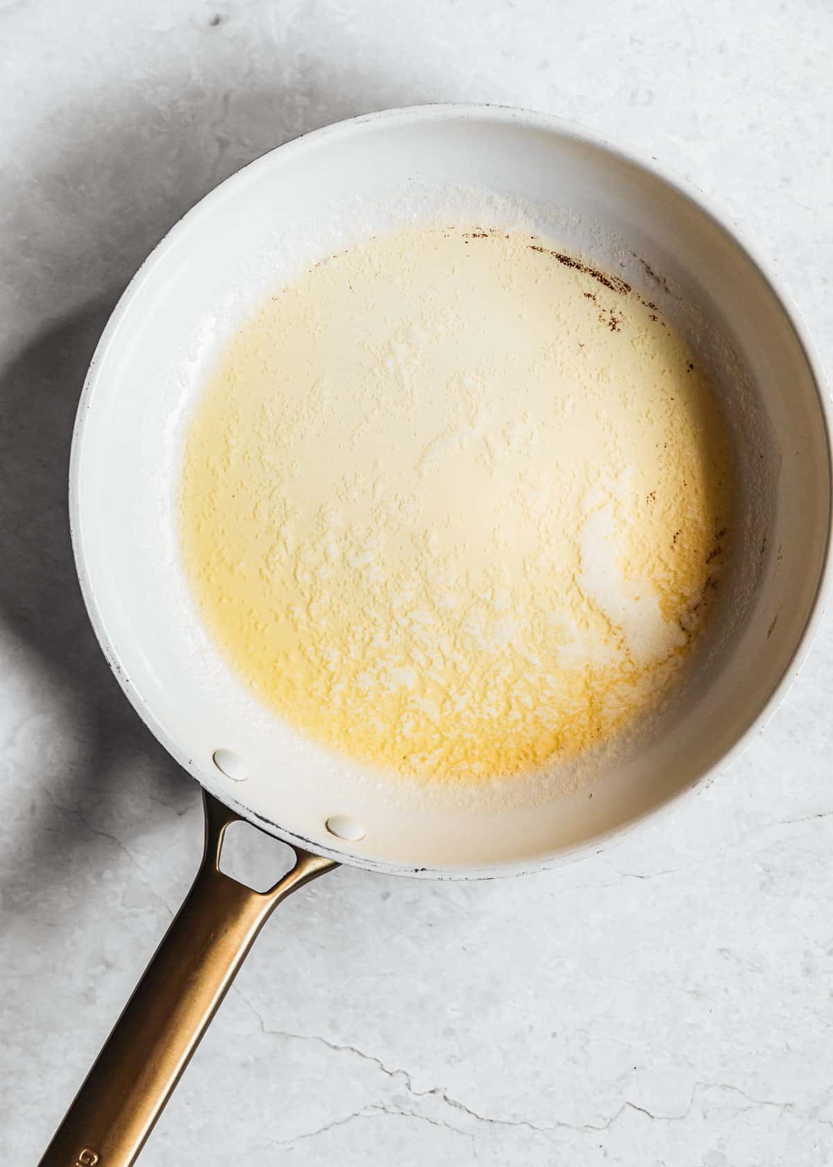 A white pan of melted butter on a white counter.