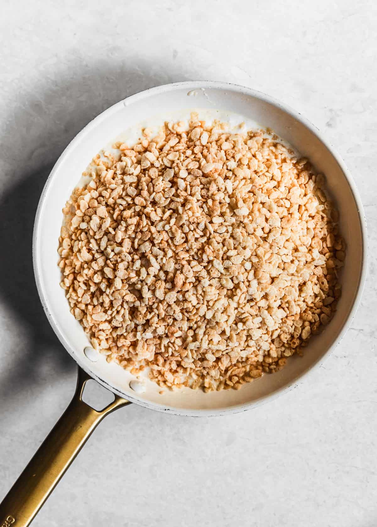 A white pan with marshmallows and cereal on a marble background.