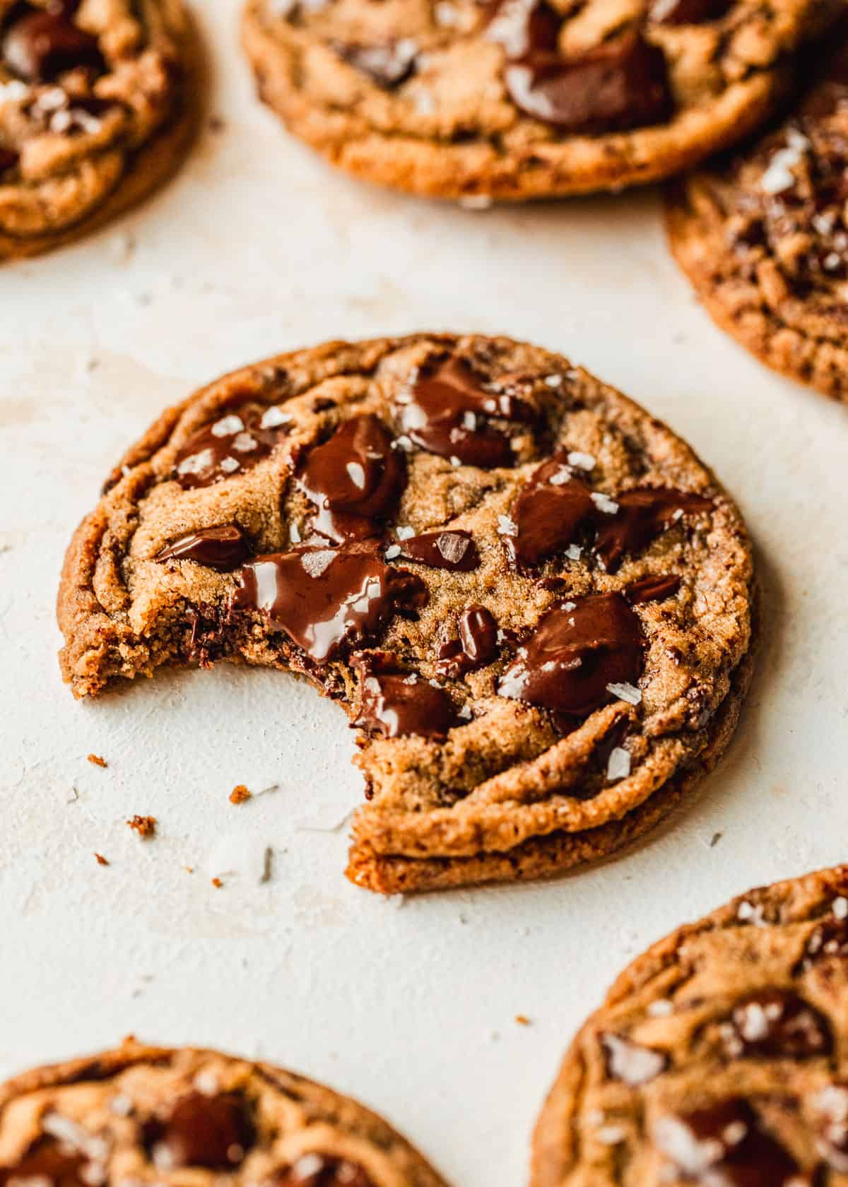 Rows of baked small batch chocolate chip cookies on a tan counter.