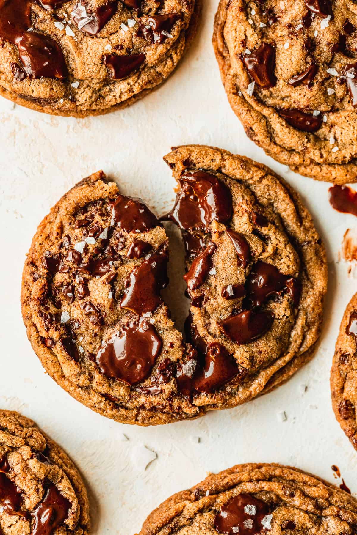 A halved cookie on a tan counter next to small batch chocolate chip cookies.