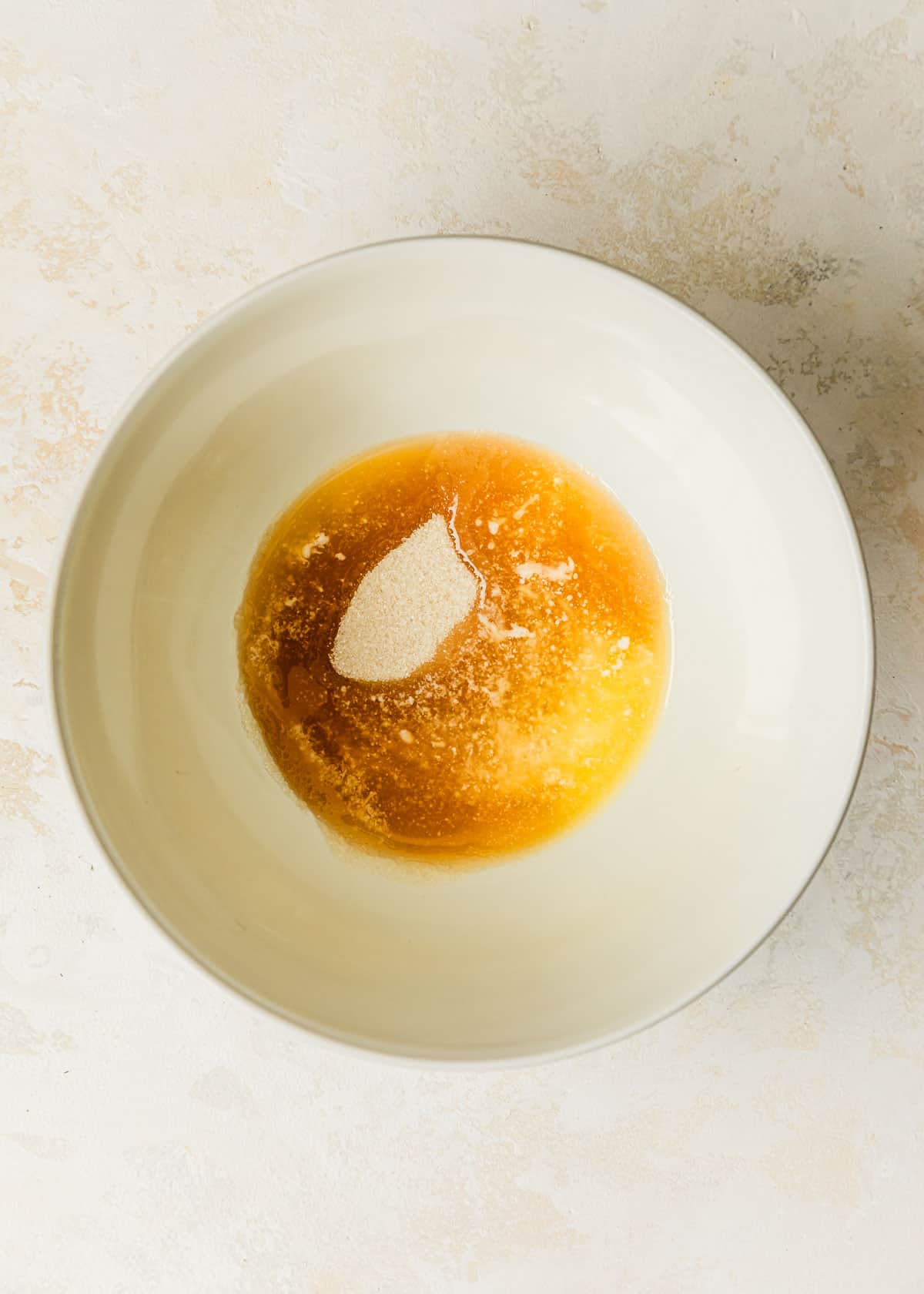 A white bowl of brown butter and sugar on a tan counter.