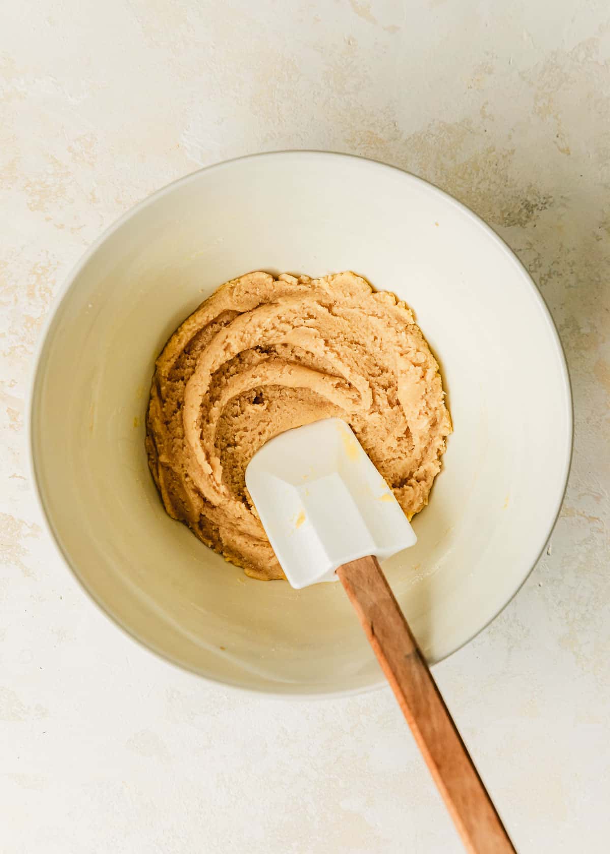 A white bowl of small batch snickerdoodles cookie dough on a tan counter.