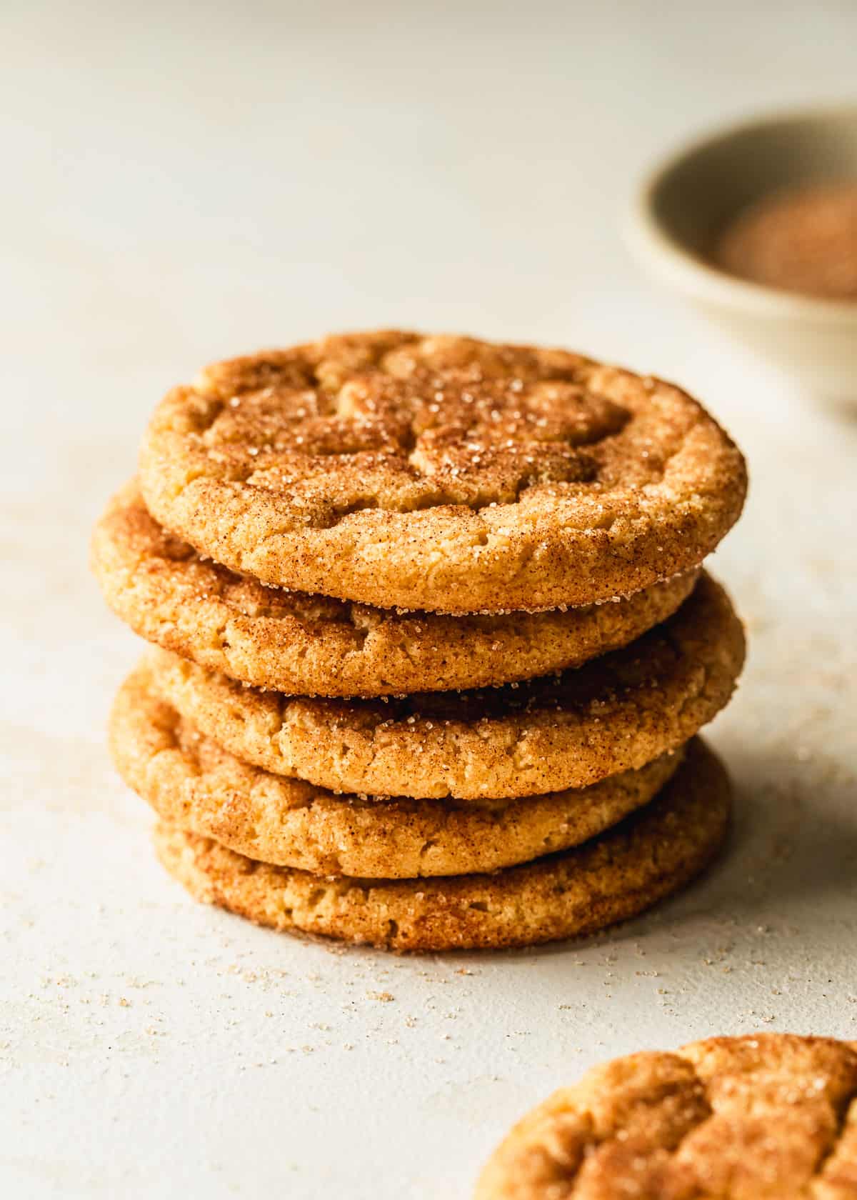A stack of small batch snickerdoodles on a tan counter.