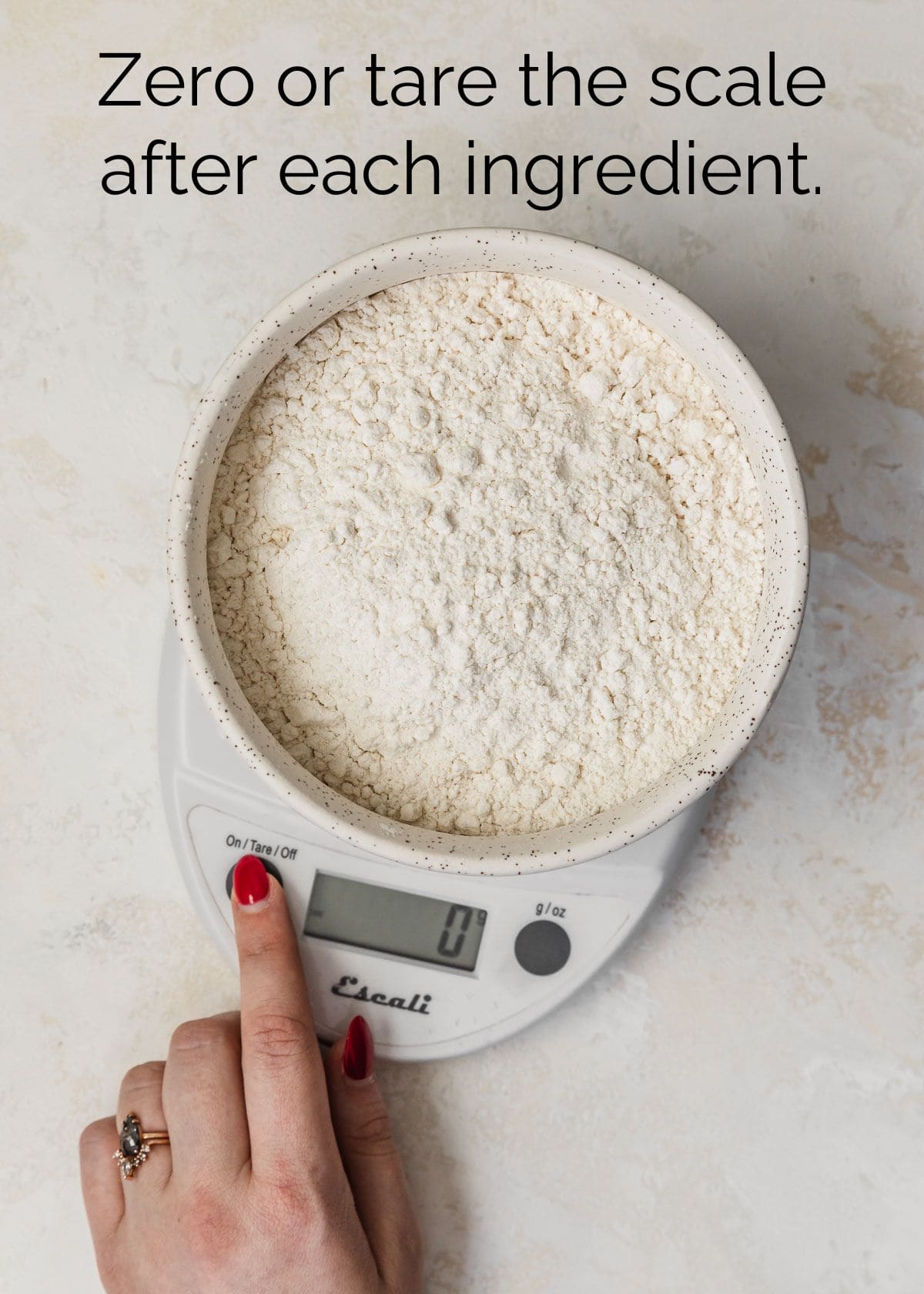 How to measure ingredients for small batch baking. A hand taring a kitchen scale.