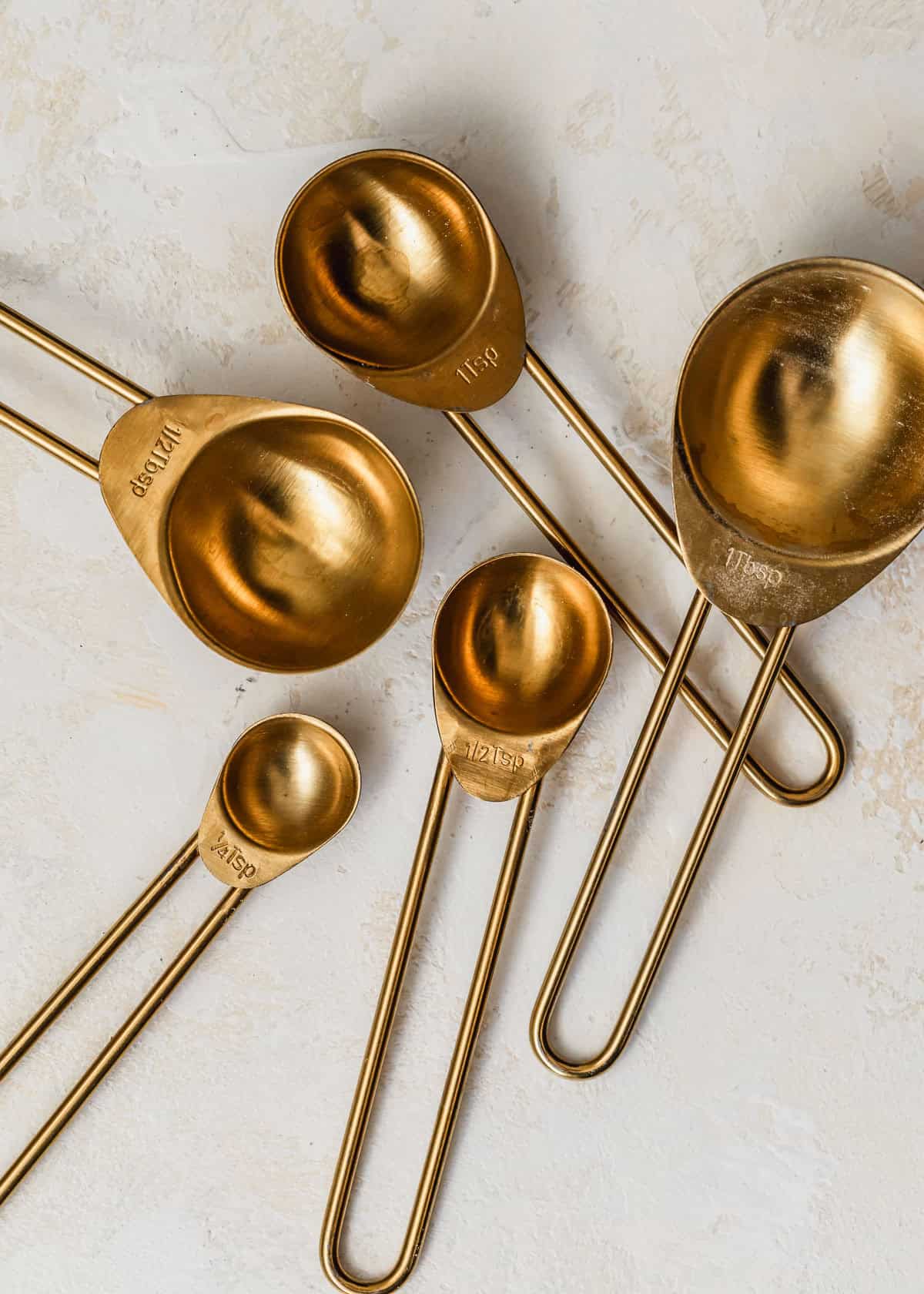 Gold teaspoons on a tan table.
