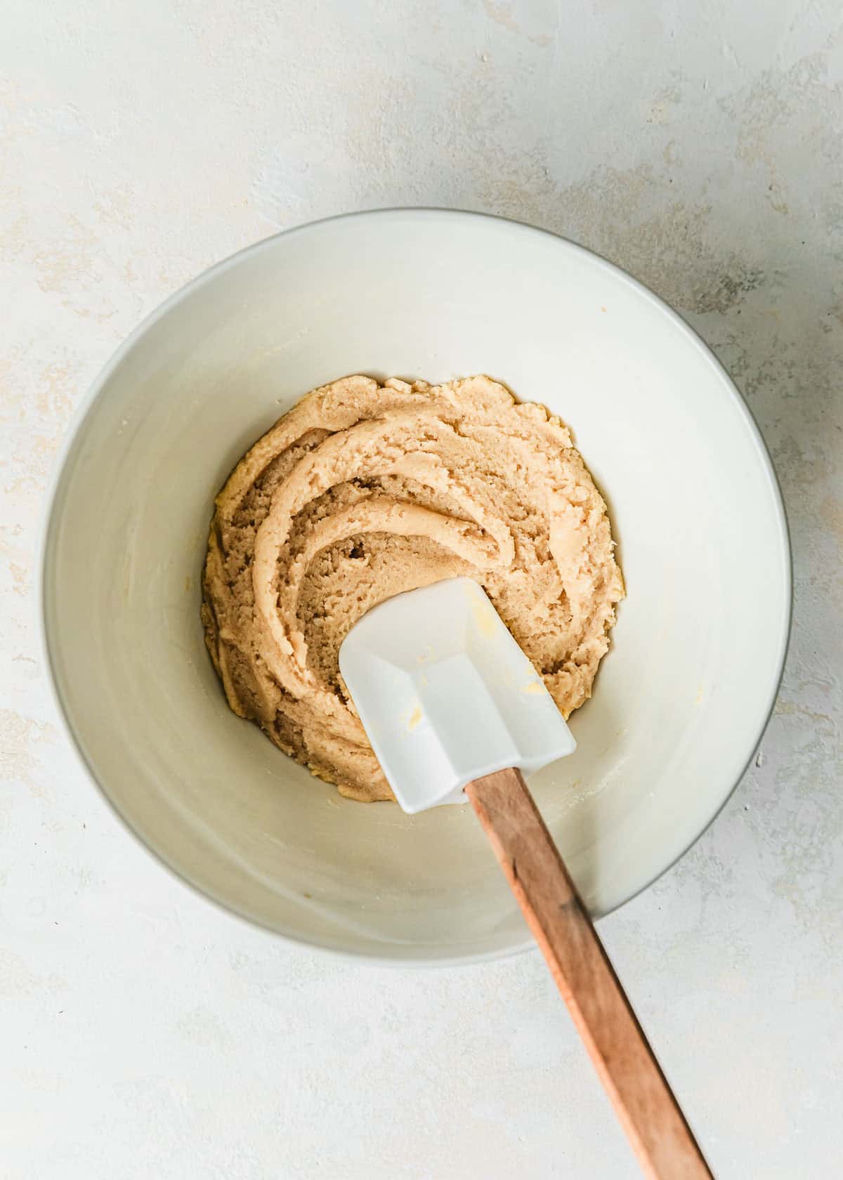 A white bowl of small batch sugar cookies dough on a white counter.