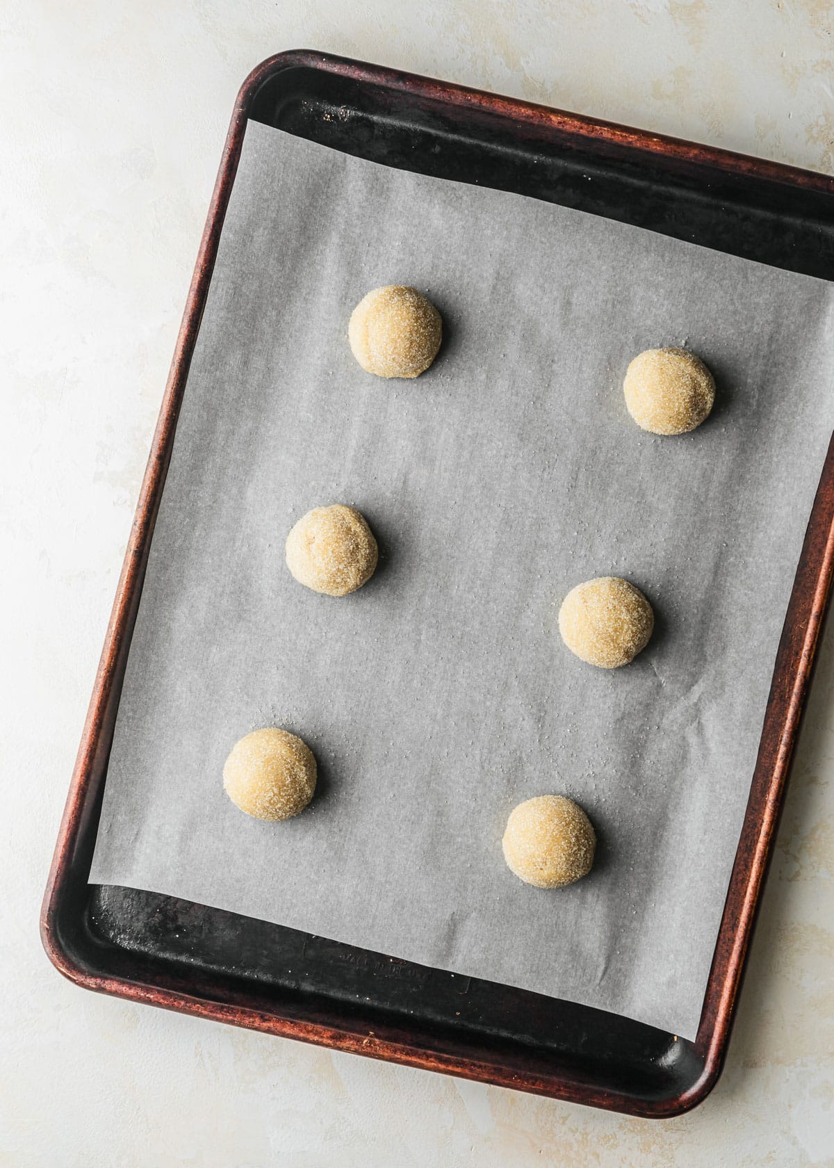 A sheet pan with 6 raw small batch sugar cookies.