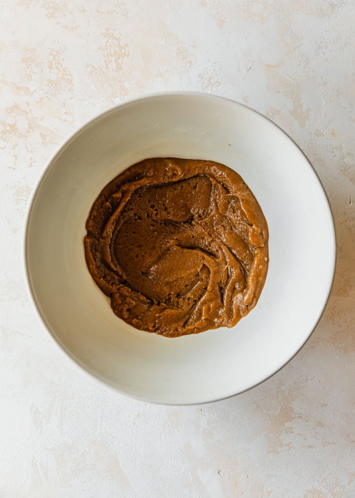 A white bowl of dough for small batch chocolate chipless cookies on a tan counter.