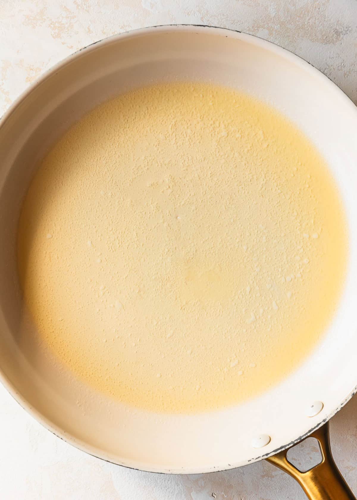 A white pan of melted butter on a tan counter.