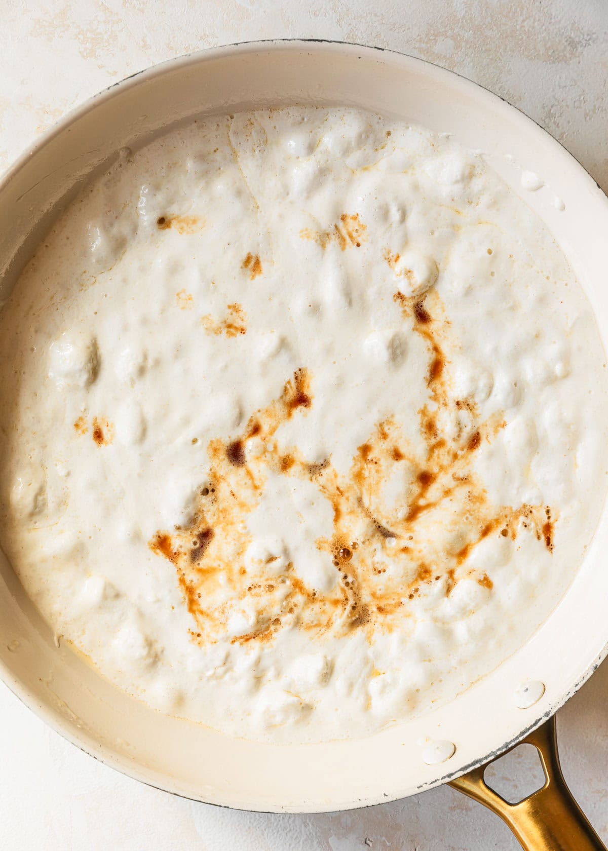 A white pan of melted marshmallows and vanilla on a tan counter.