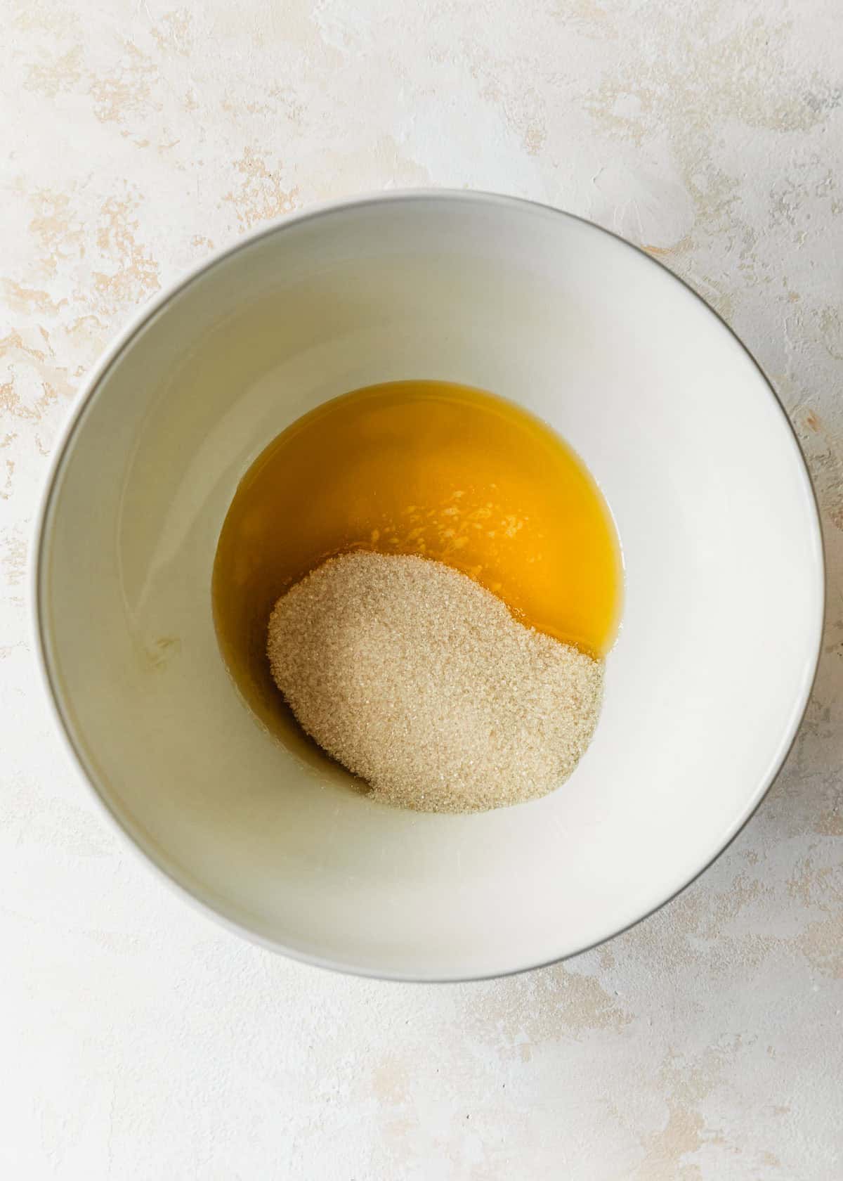A white bowl of melted butter and sugar on a beige counter.