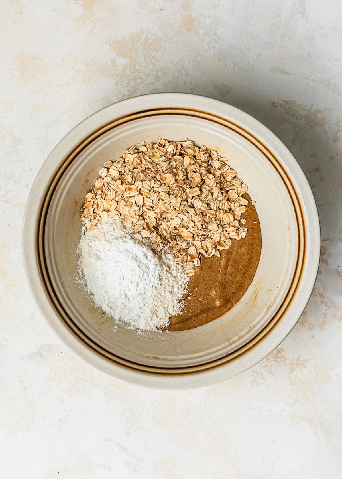 A white bowl of butter, sugar, oats, and flour for small batch oatmeal cookies.