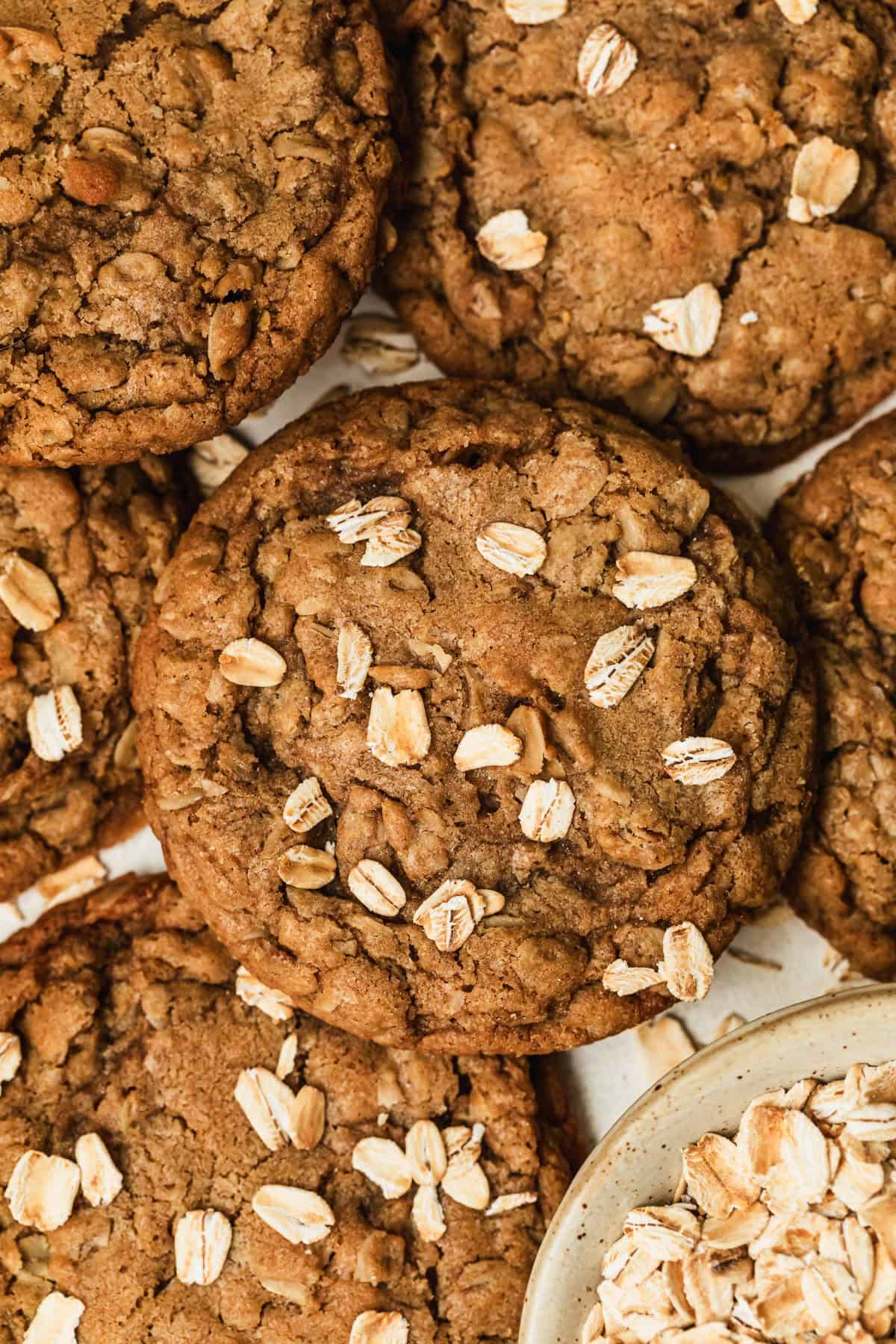 Small batch oatmeal cookies stacked on top of each other next to a white bowl of oats.