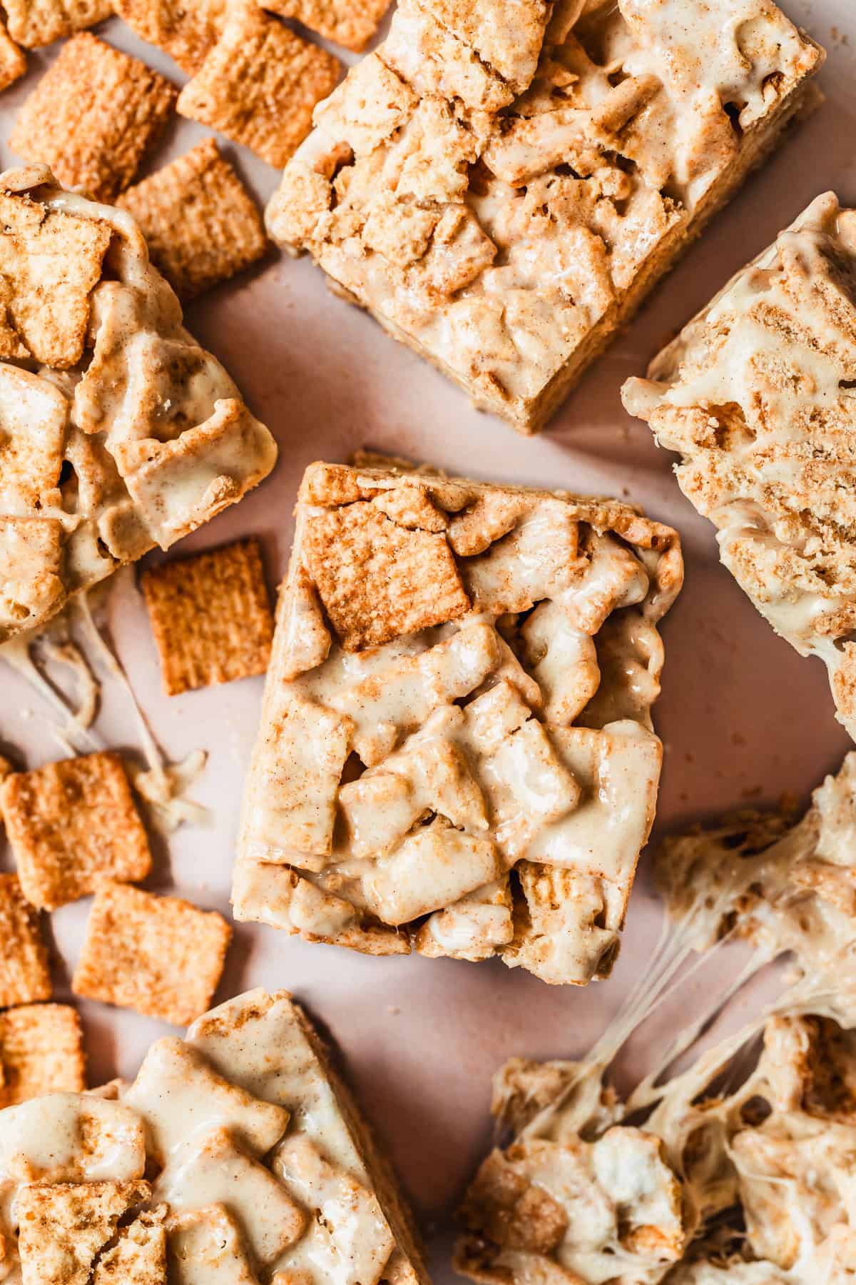 Rows of small batch cinnamon toast crunch marshmallow treats on a pink counter.