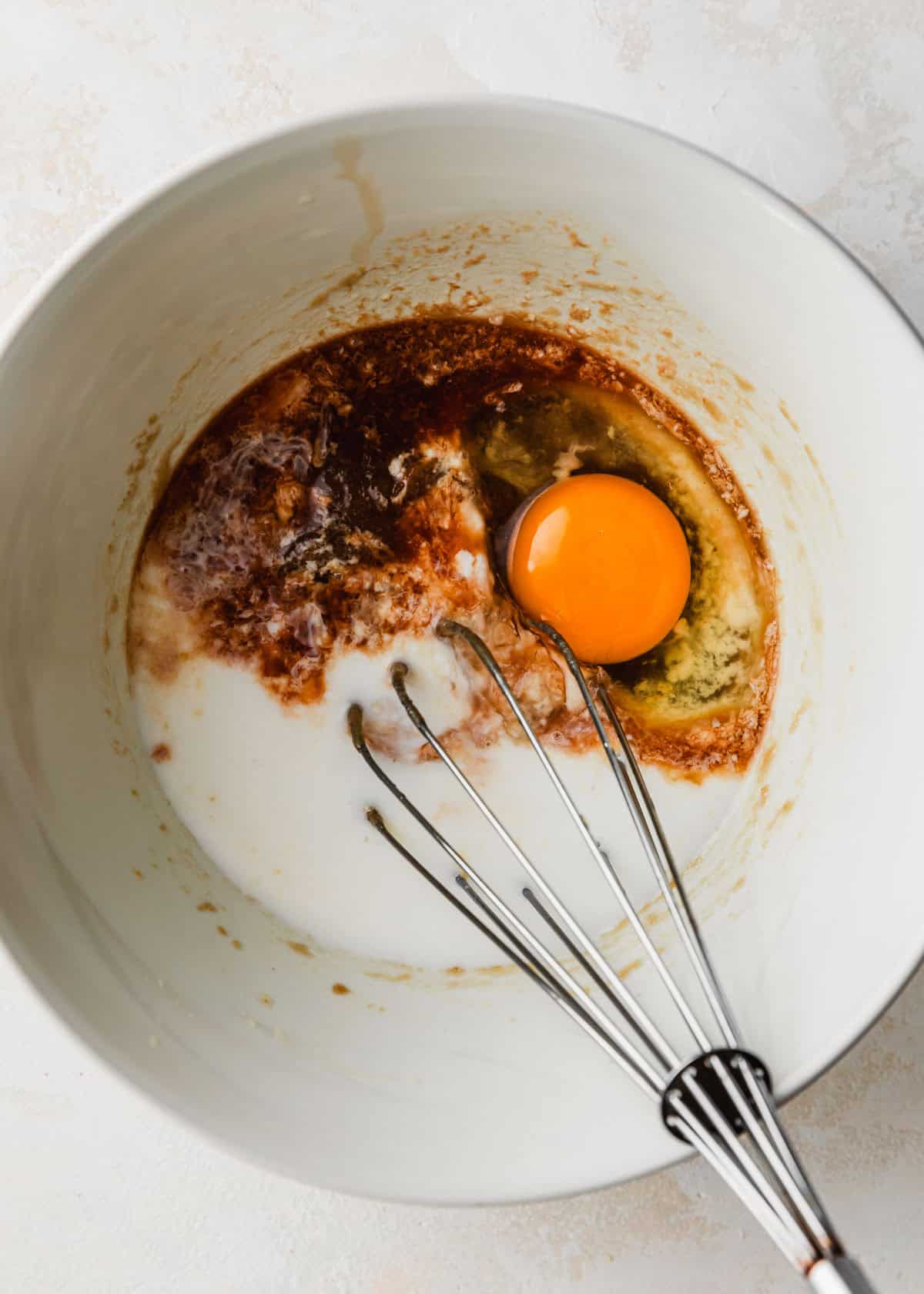 A white bowl with butter, brown sugar, buttermilk, vanilla, and an egg.