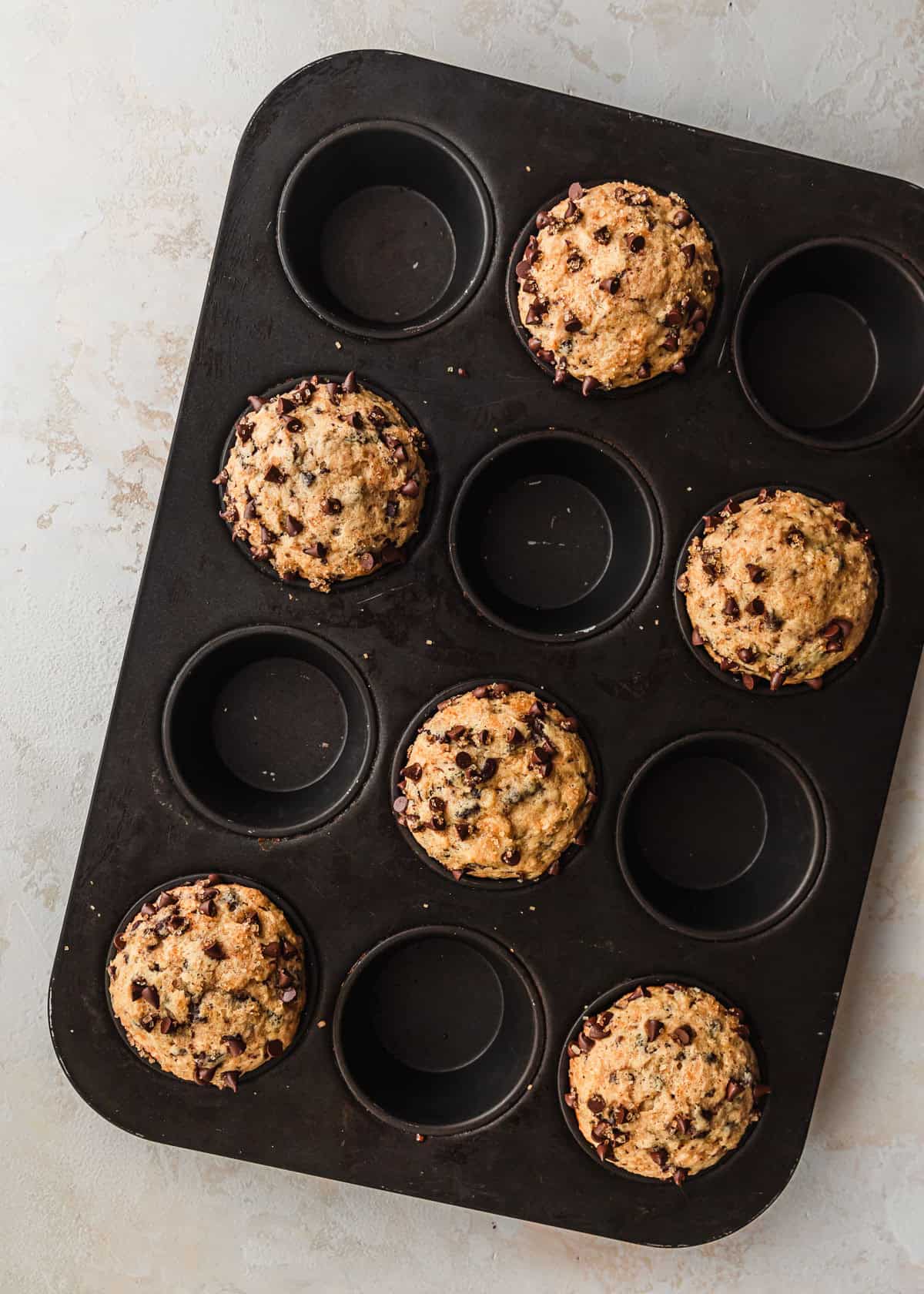 A pan of small batch chocolate chip muffins on a beige table.