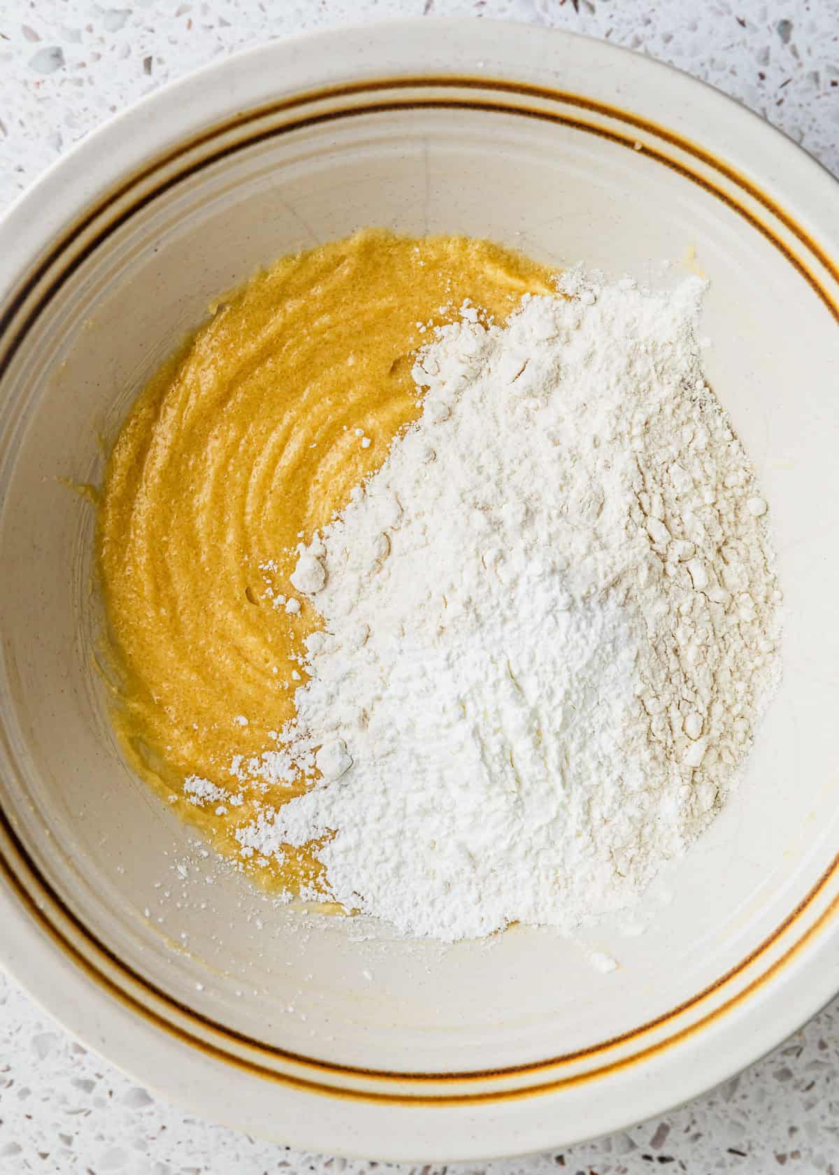 A white bowl of butter, sugar, egg yolk, vanilla, flour, baking soda, salt, & cornstarch.