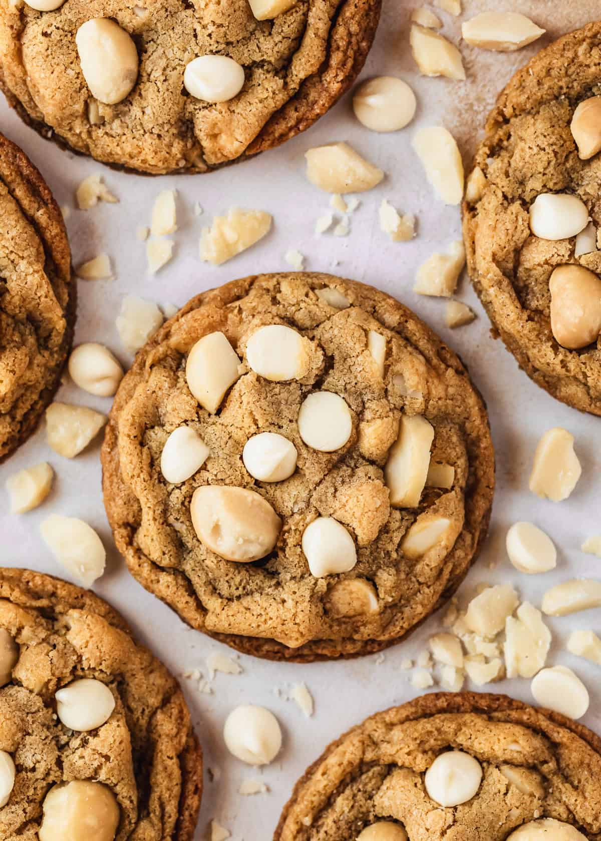 Six small batch white chocolate macadamia nut cookies on a pink counter.