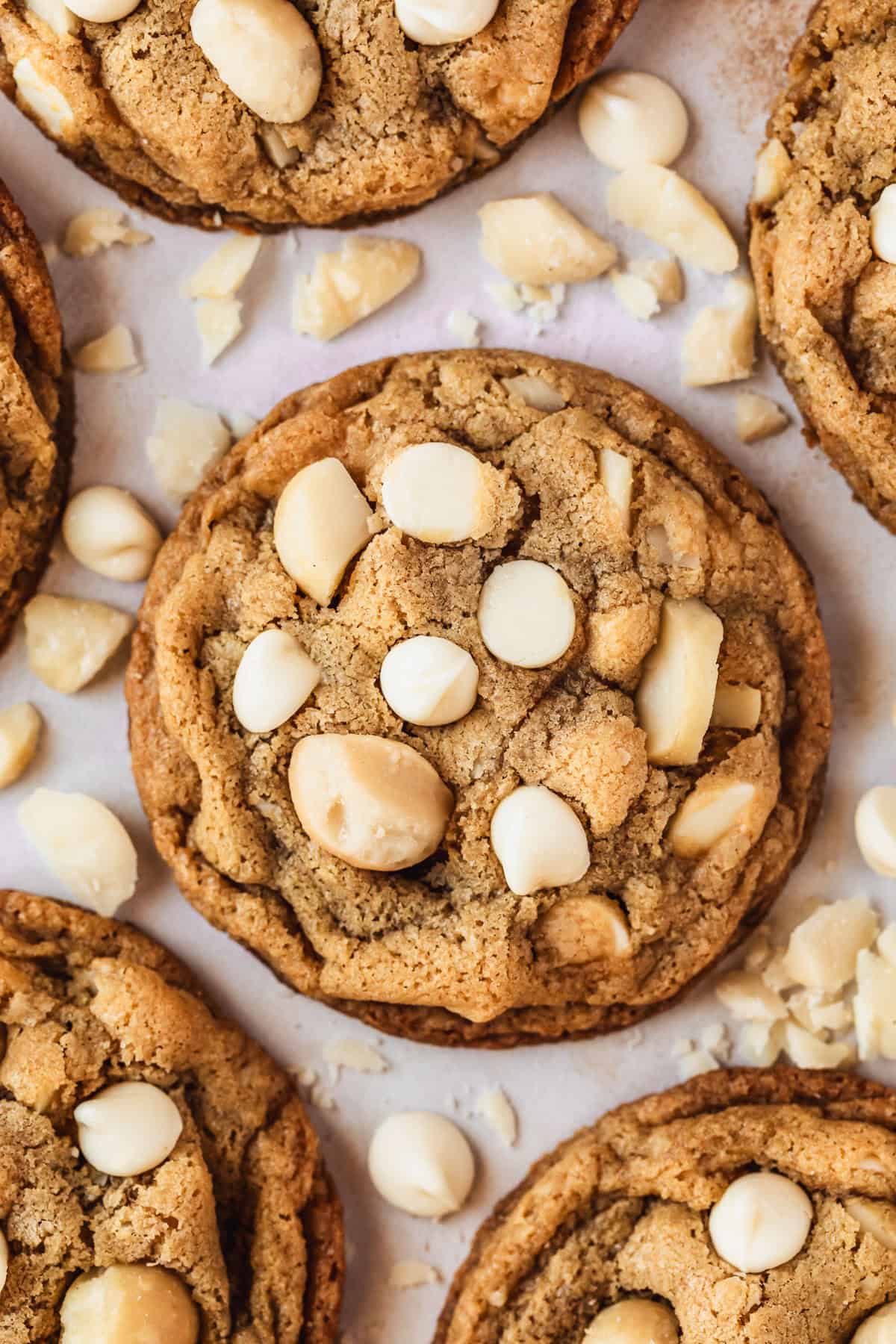 Rows of small batch white chocolate macadamia nut cookies on a pink counter.