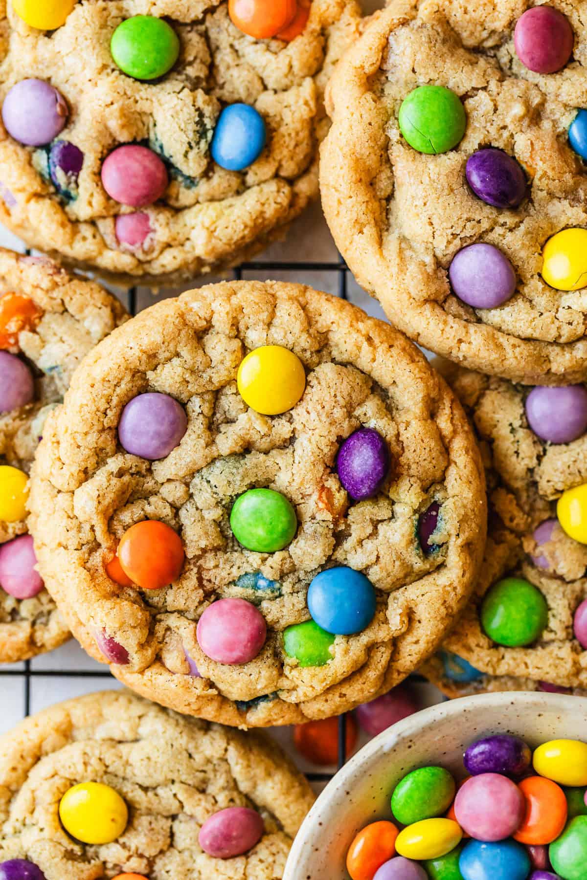 Rows of small batch M&M cookies stacked on a wire rack.