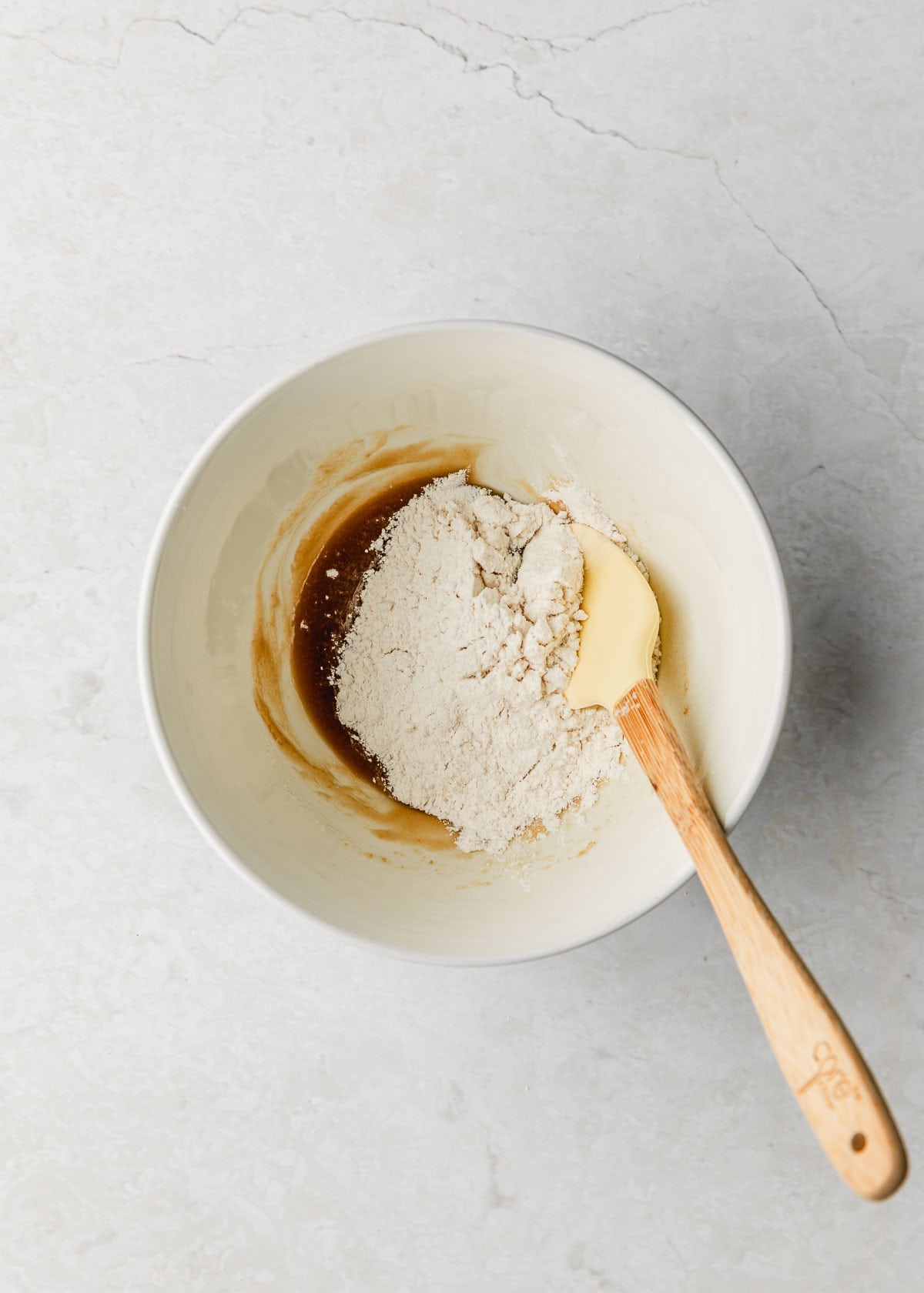 A white bowl of butter, sugar, cream, and flour on a marble counter.