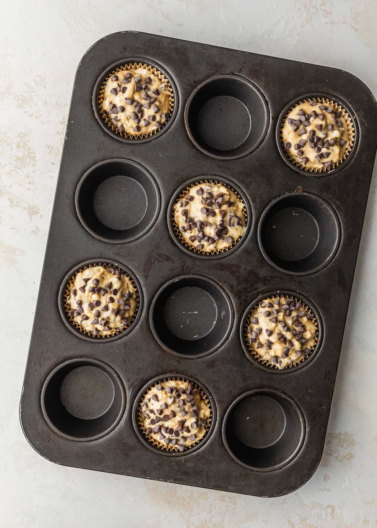 A pan of 6 muffins topped with chocolate.