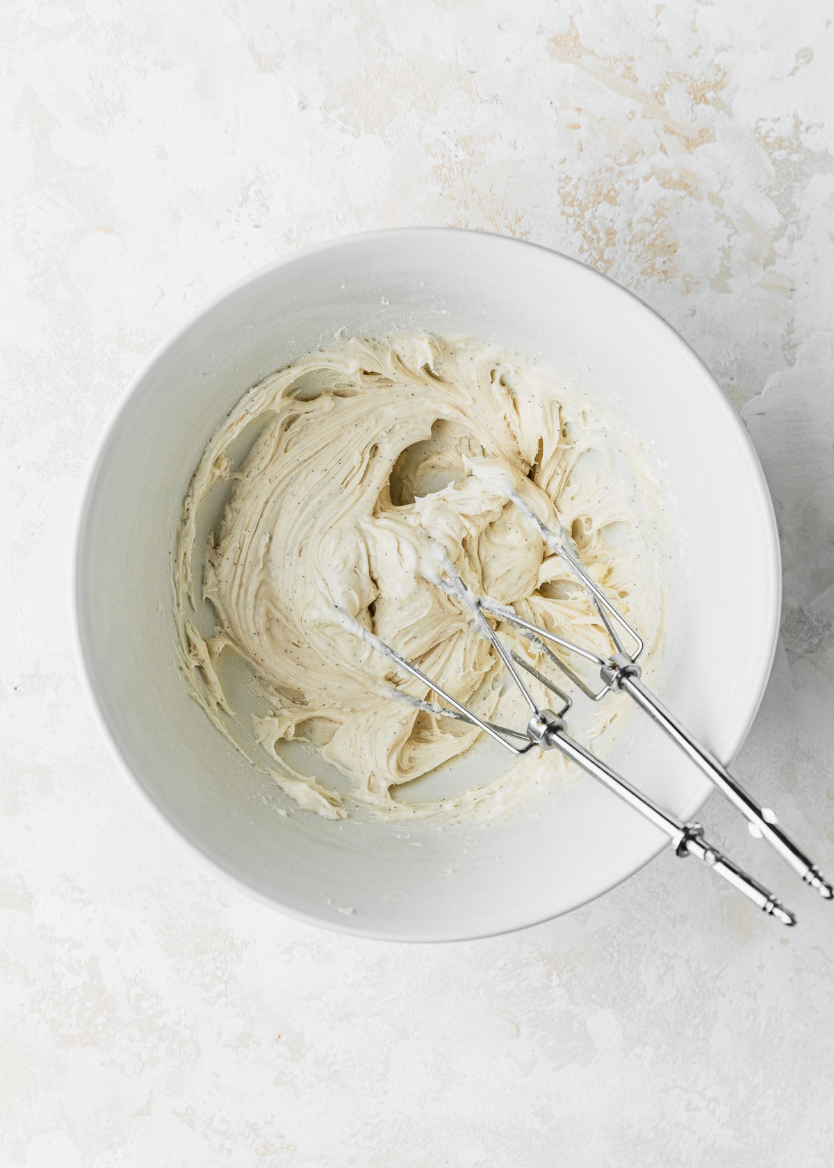A white bowl of small batch vanilla frosting on a white counter.