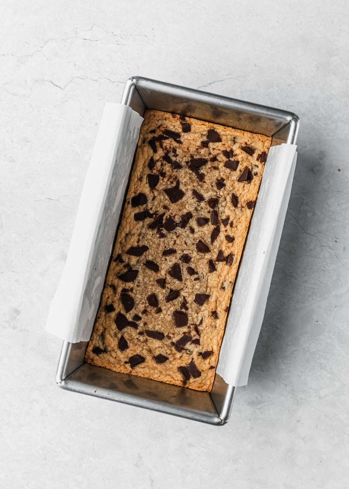 A pan of baked small batch chocolate chip cookie bars on a marble table.