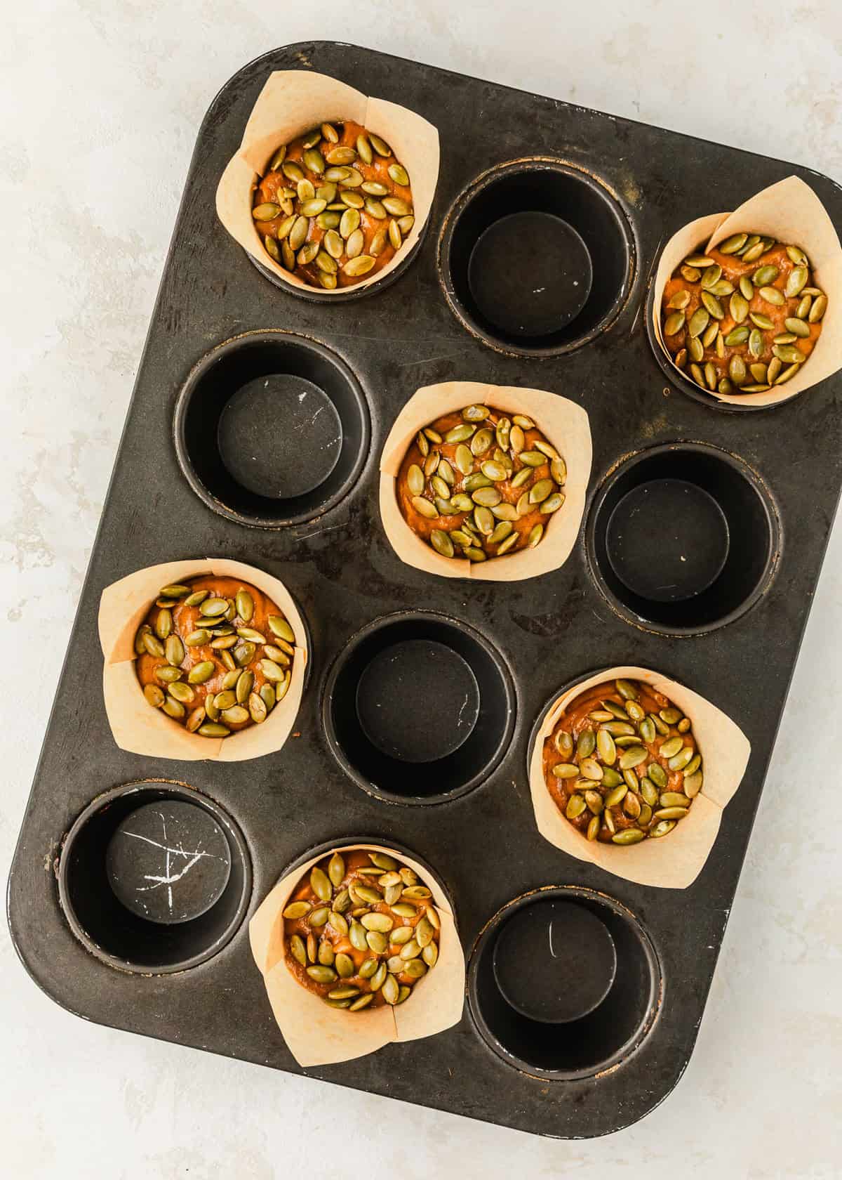 A pan of raw small batch pumpkin muffins on a tan counter.