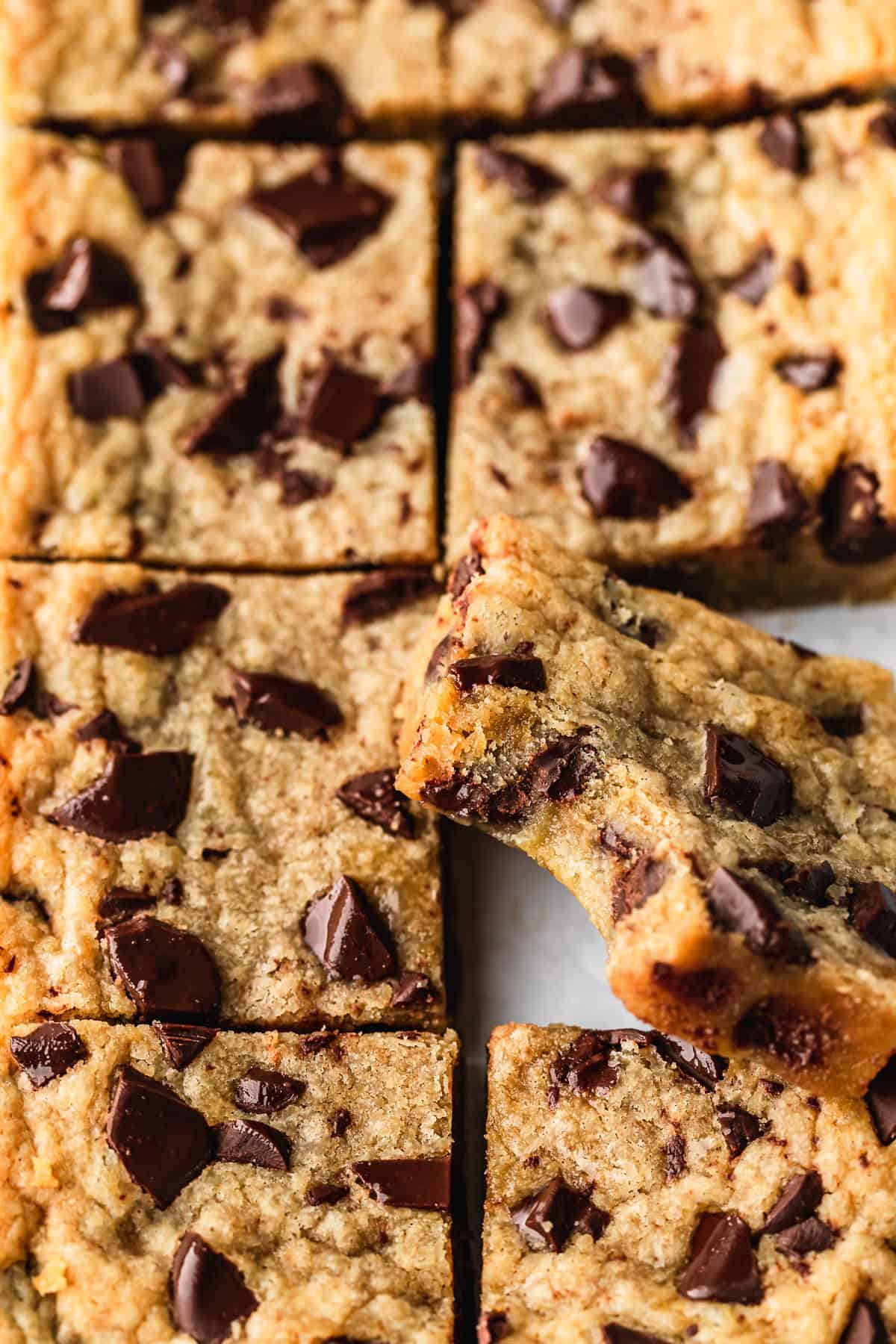A cookie bar with a bite taken out of it leaned against two rows of small batch chocolate chip cookie bars.