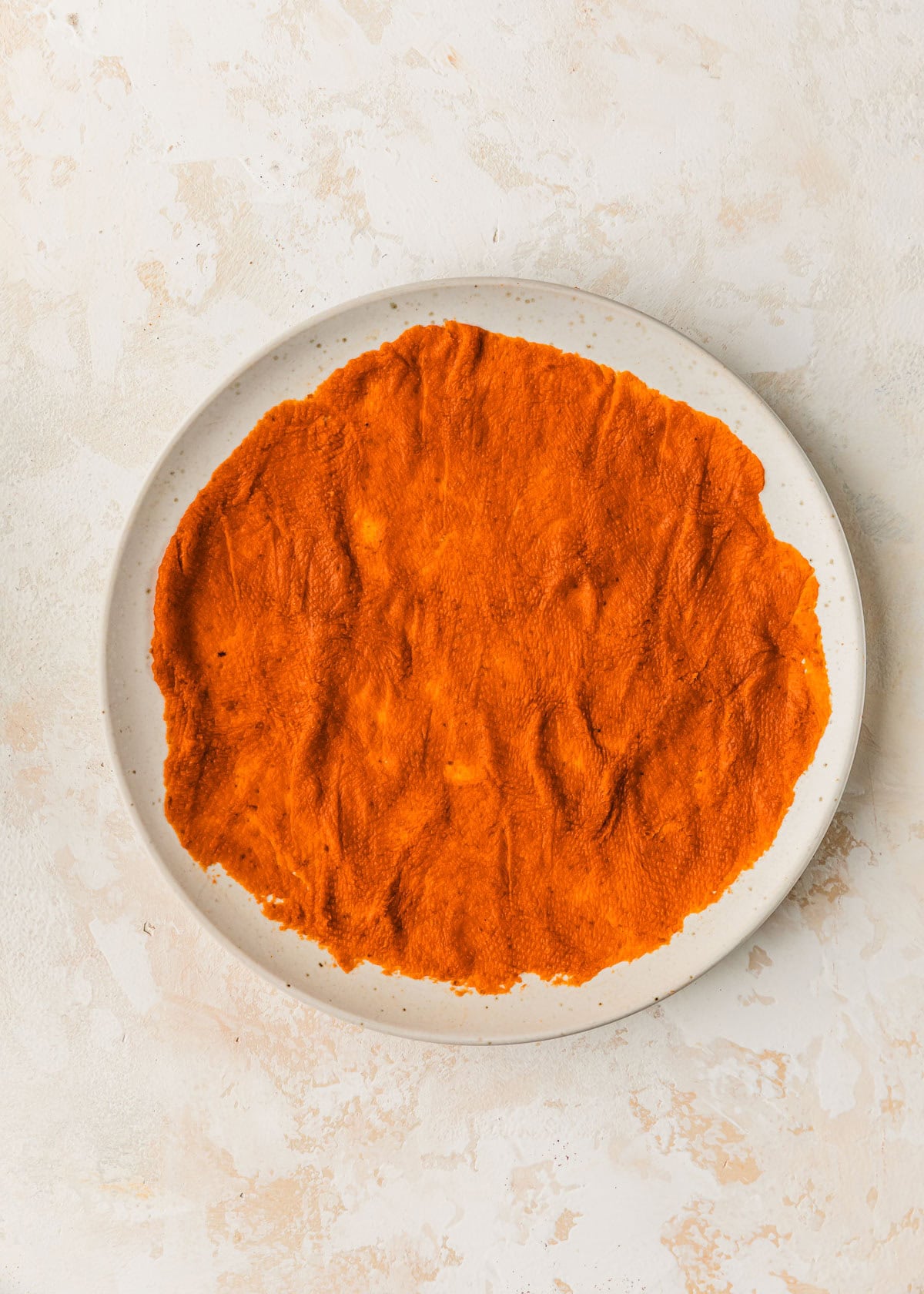 A white plate of pumpkin puree with the water removed.