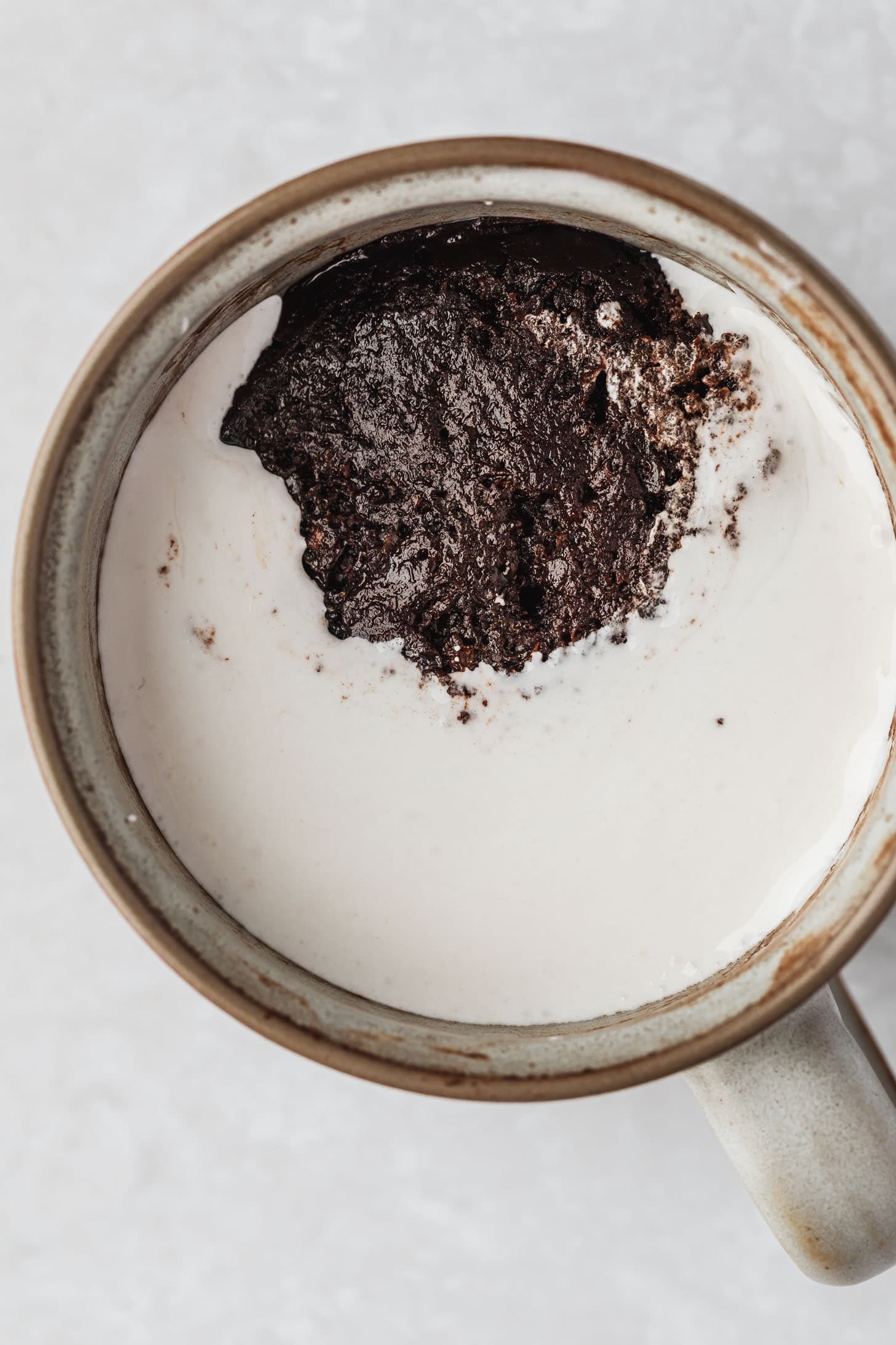A grey mug with hot chocolate cake and marshmallow.