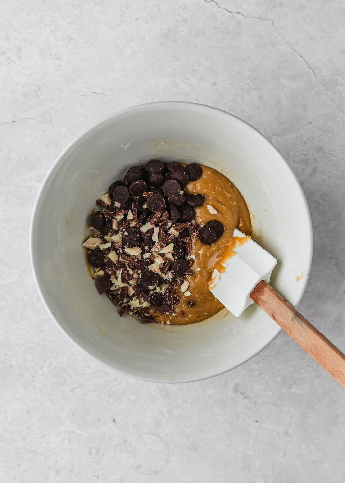 A white bowl of dough for small batch peppermint bark chocolate chip cookies with a white background.