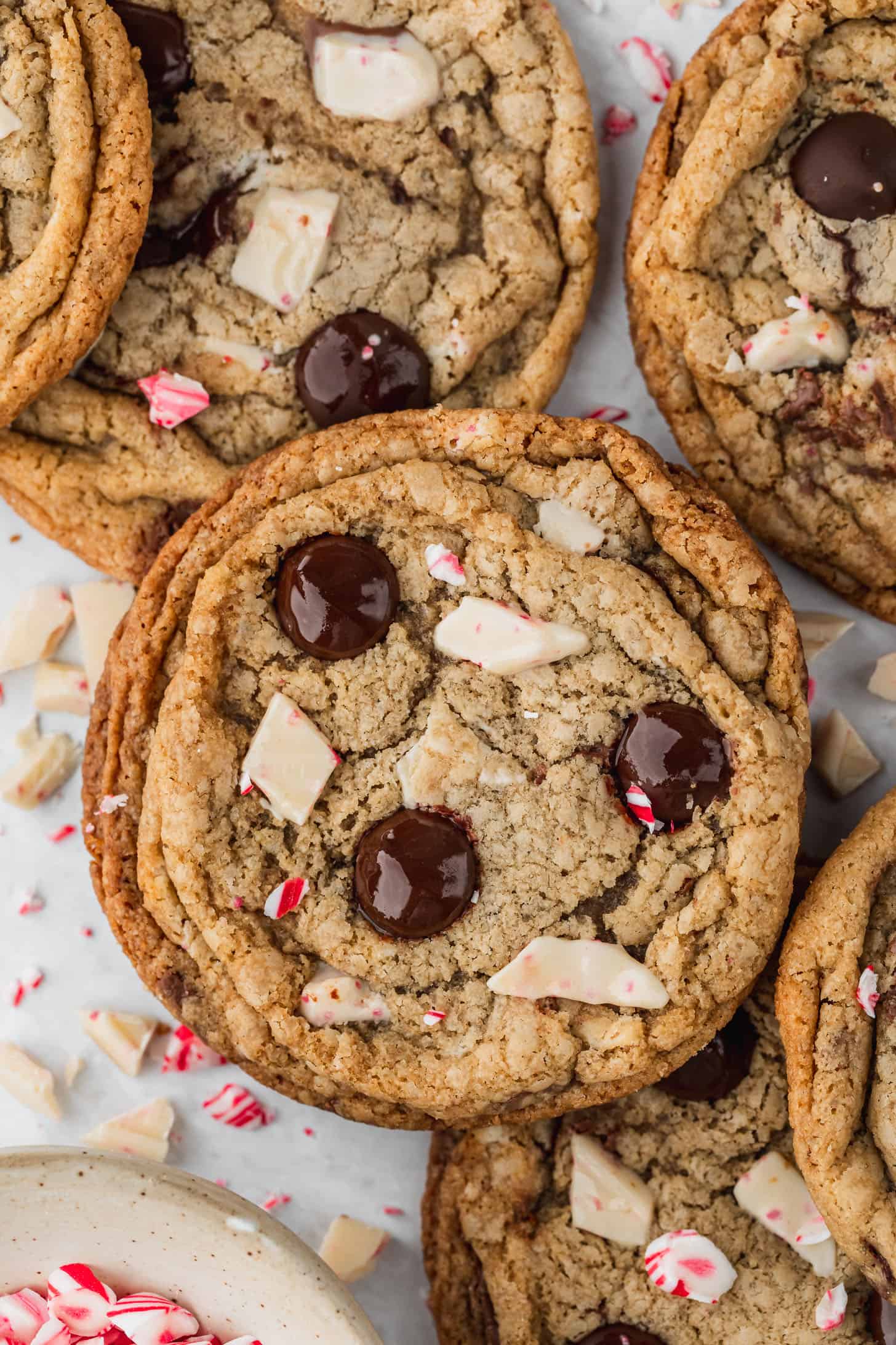 Rows of small batch peppermint chocolate chip cookies and a white bowl of candy canes on a white counter.