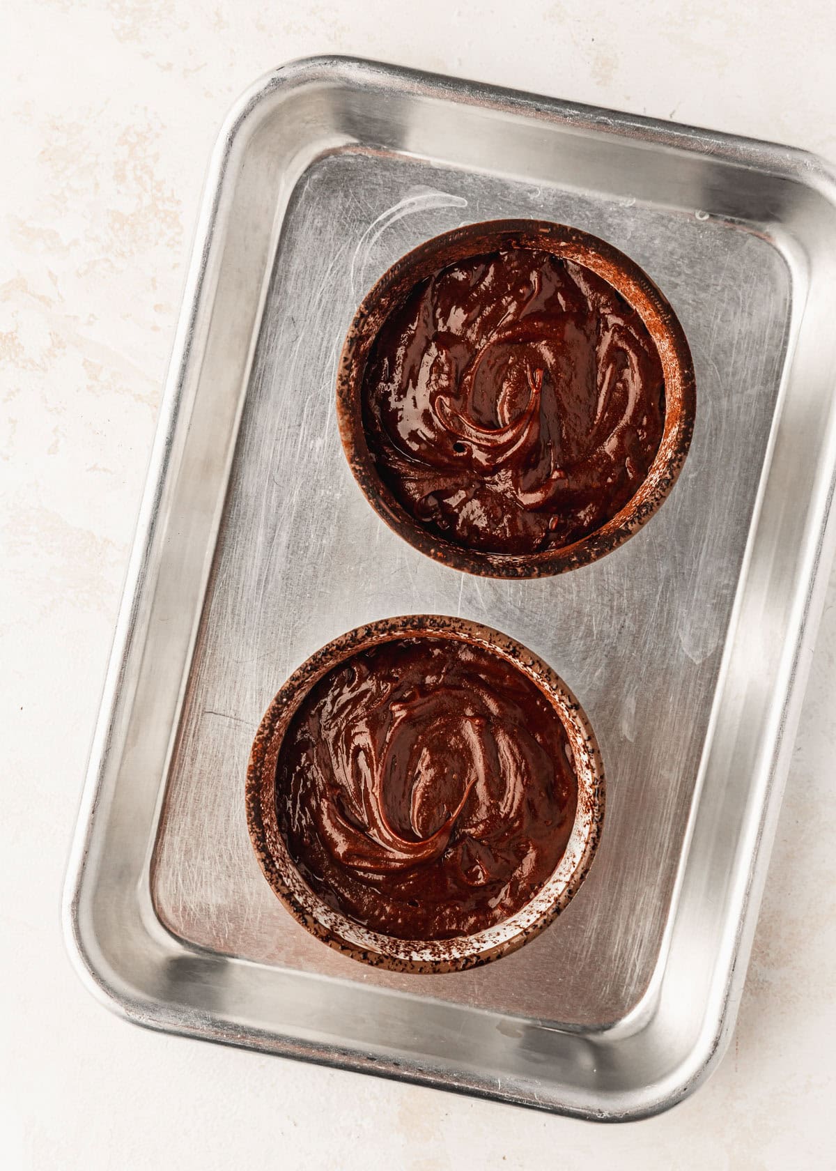 A sheet pan with unbaked lava cakes for two.