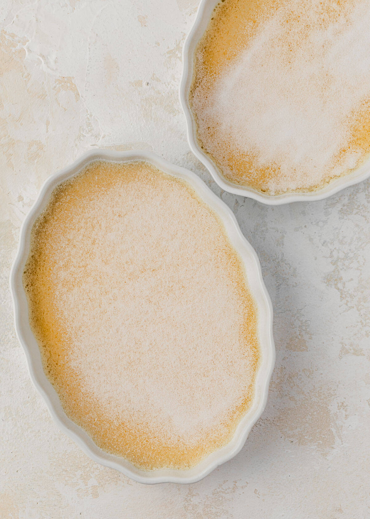 Two ramekins of crème brûlée with raw sugar.