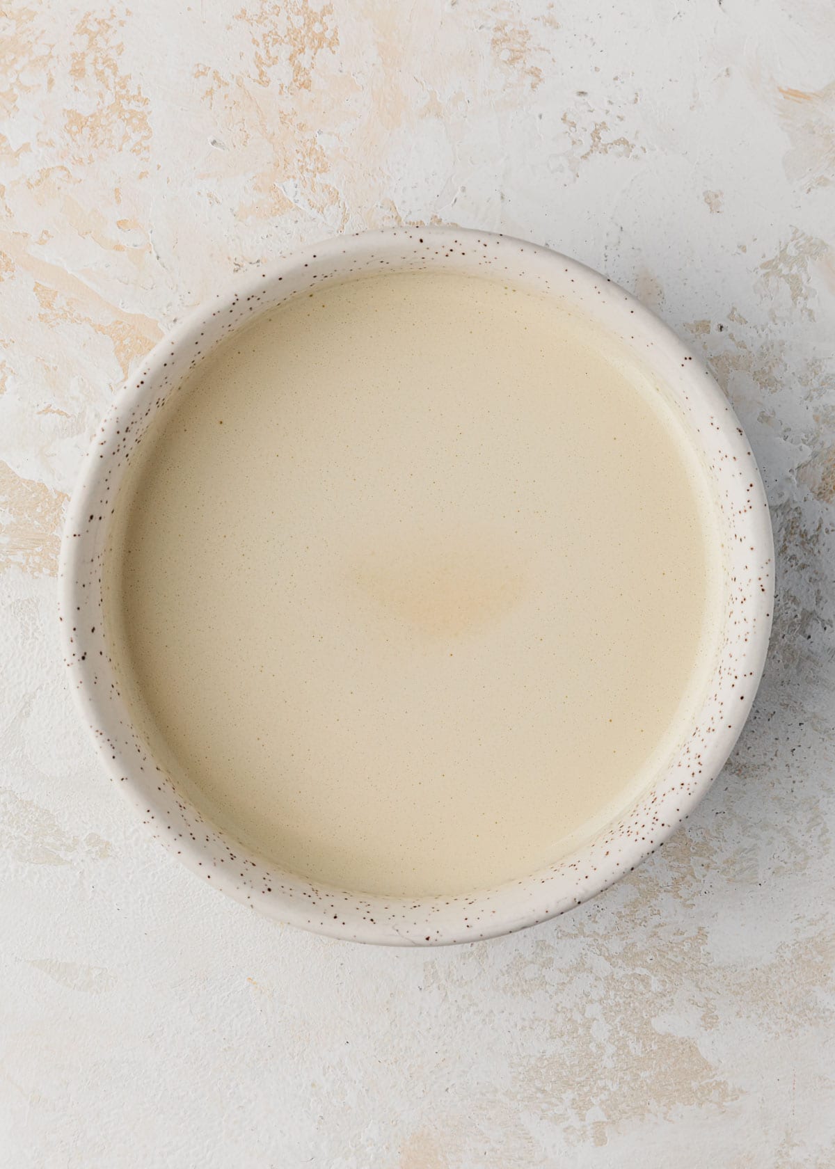 A white bowl of custard for creme brulee for two.