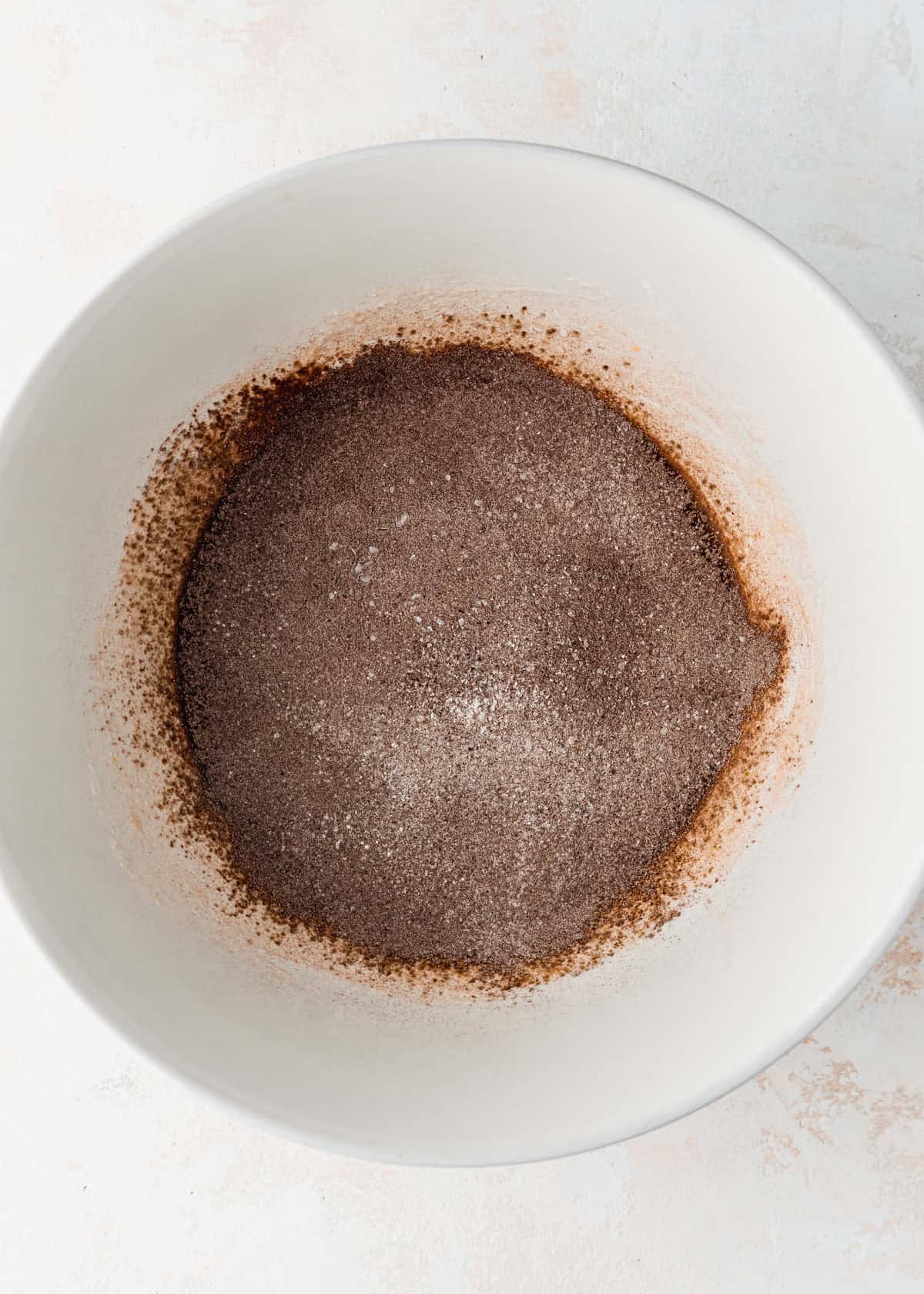 A white bowl of flour and cocoa powder on a white counter.