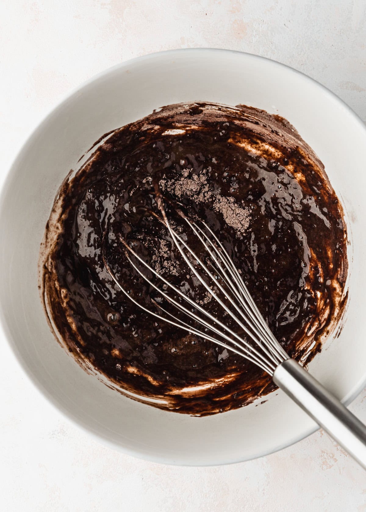 A white bowl of chocolate batter on a white counter.