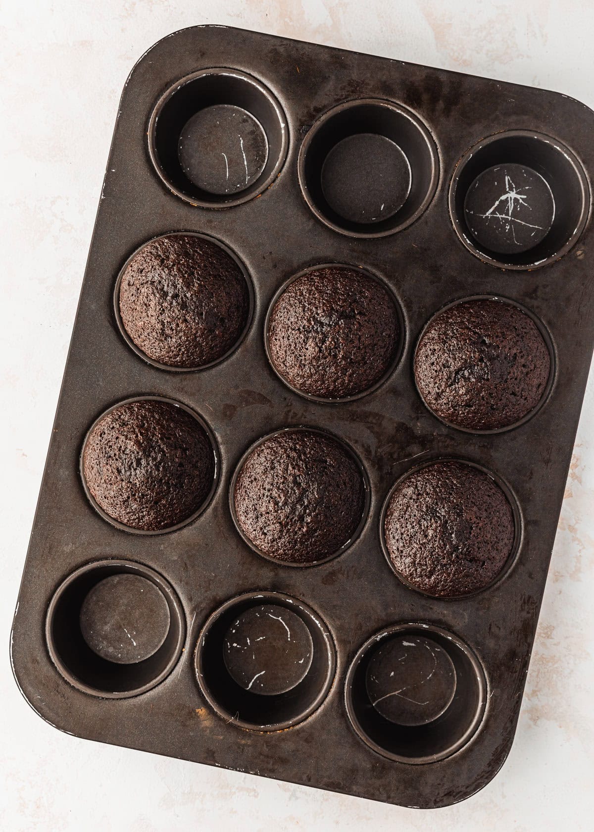 A pan of baked small batch chocolate cupcakes on a beige counter.