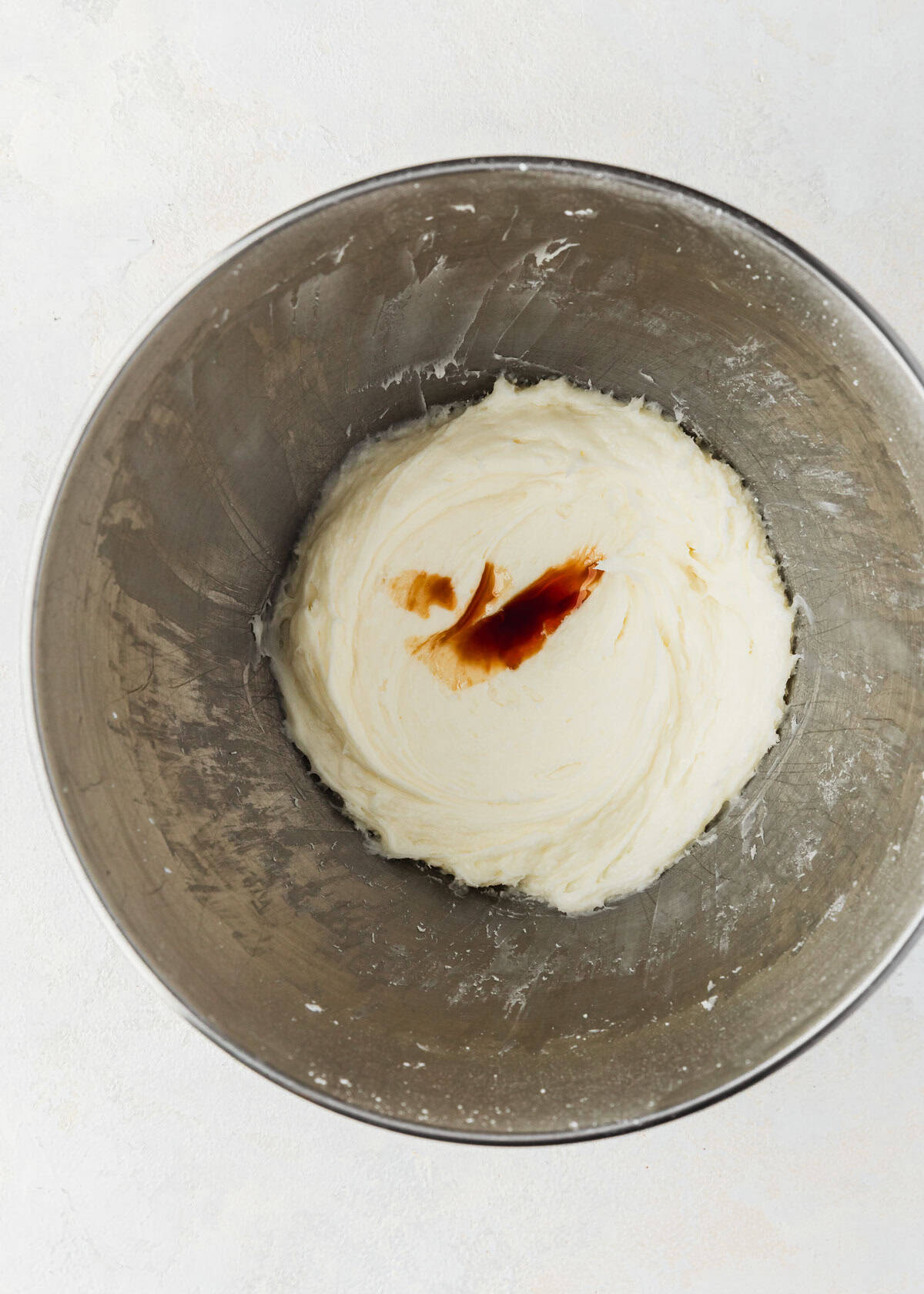 A silver bowl of small batch cream cheese frosting with vanilla extract.