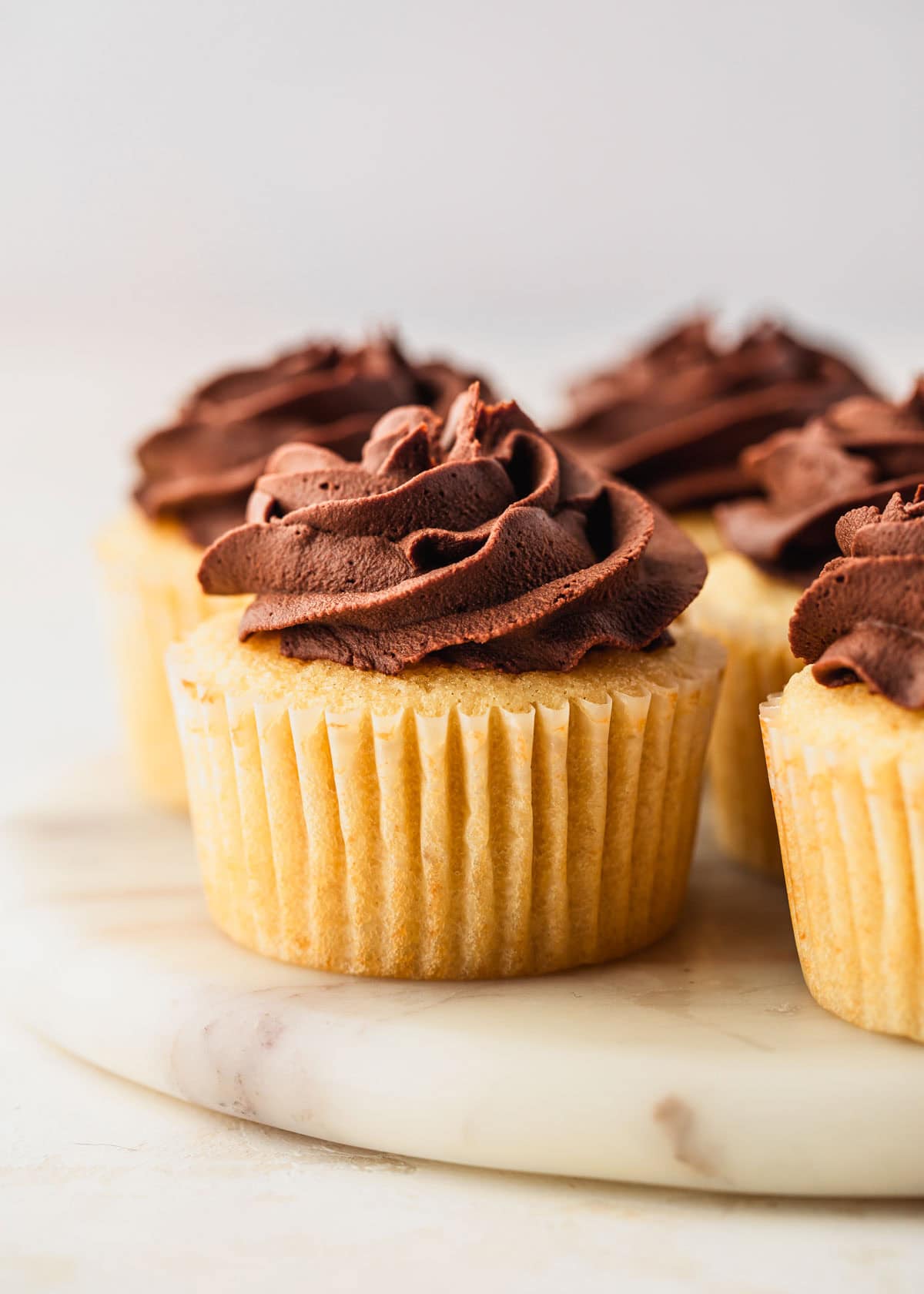 A white platter of undecorated small batch Easter egg cupcakes on a white counter.