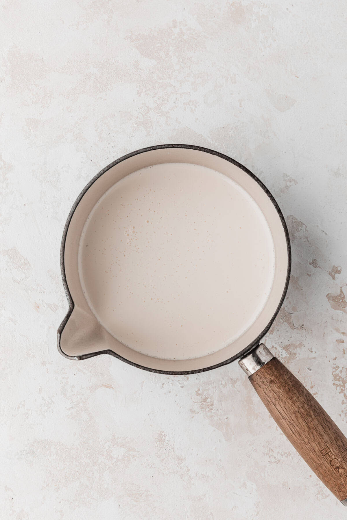 A sauce pan of heavy cream on a white counter.